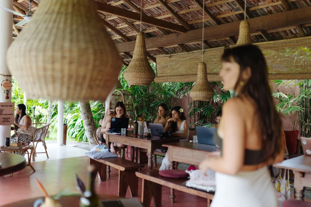 Women working on laptops at a tropical outdoor cafe with hanging wicker lamps — Casa Tikiri, Ahangama, Sri Lanka