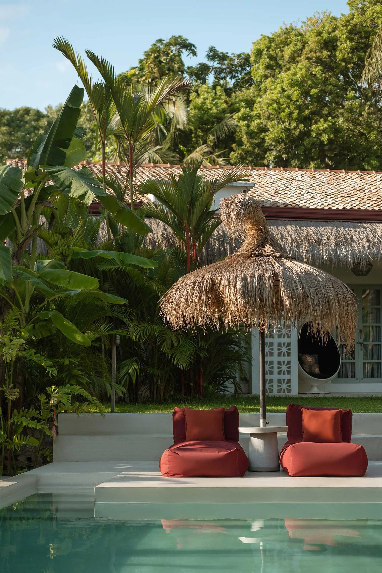 Swimming poolside with red lounge chairs and thatched parasol — Casa Tikiri Boutique Hotel, Ahangama, Sri Lanka