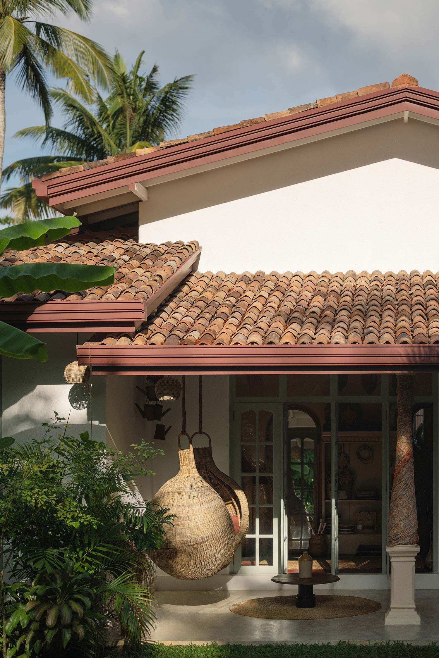 House with red tile roof, tropical plants and a hanging wicker lamp — Casa Tikiri Boutique Hotel, Ahangama, Sri Lanka