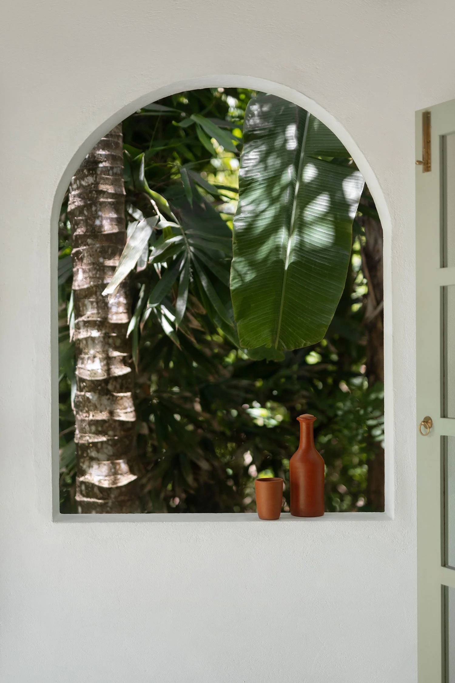 View through an arched window showing lush green foliage and tropical leaves — Casa Tikiri Boutique Hotel, Ahangama, Sri Lanka
