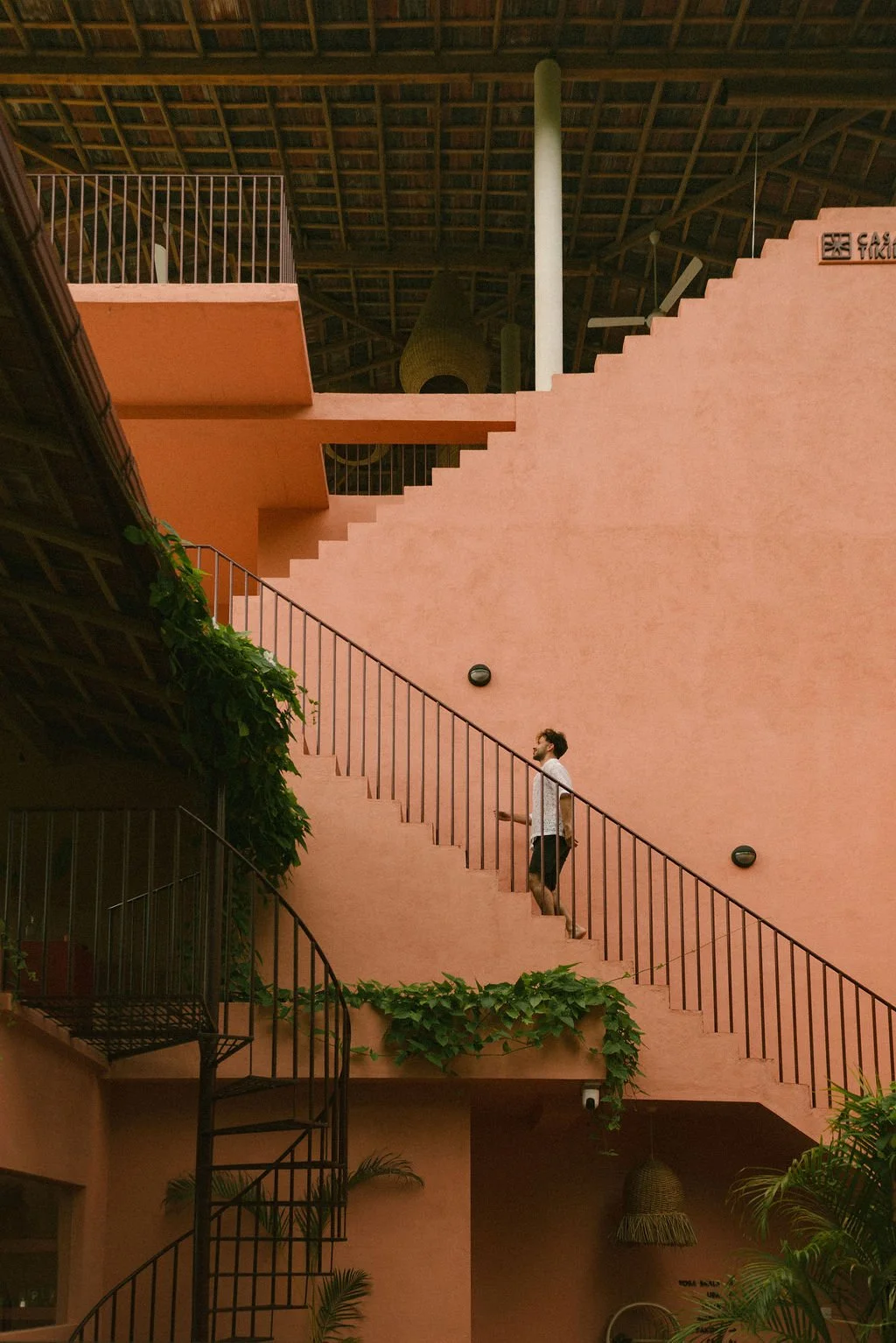 
Man in white shirt walking up outdoor pink stairs with black railings — Casa Tikiri Paddy Lodge, Ahangama, Sri Lanka