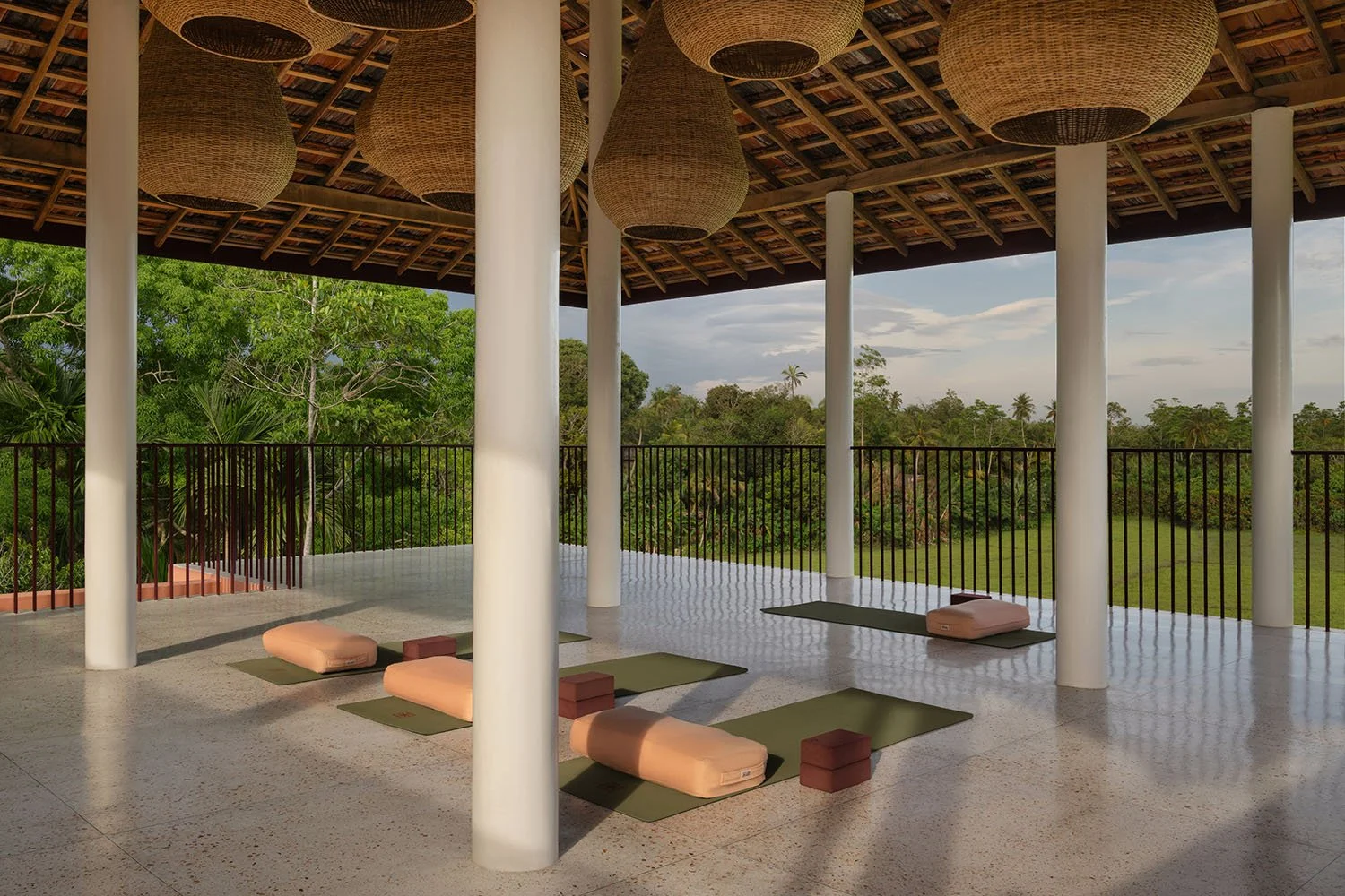 Open-air yoga deck with mats and bolsters overlooking rice fields — Casa Tikiri Rooftop Shala, Ahangama, Sri Lanka