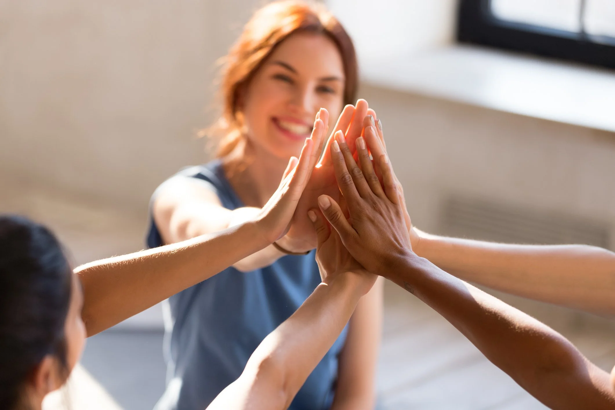 People giving high fives in a group, with a smiling woman in the background.