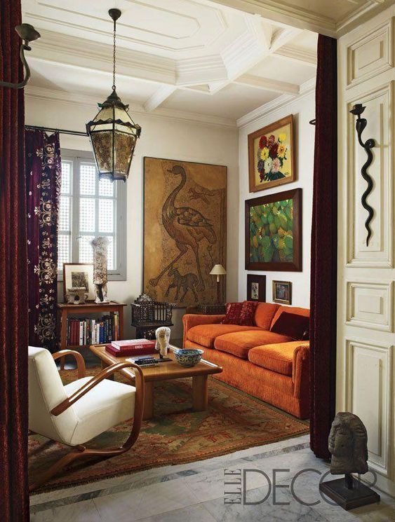 soggiorno con un mix di arredi antichi e moderni e divano arancione in velluto