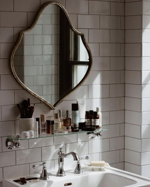 Bagno con specchio con struttura in metallo grigio lavabo in vetro su  supporti cromati cabina doccia con divisorio in vetro pavimento  piastrellato e finestra in alluminio bianco