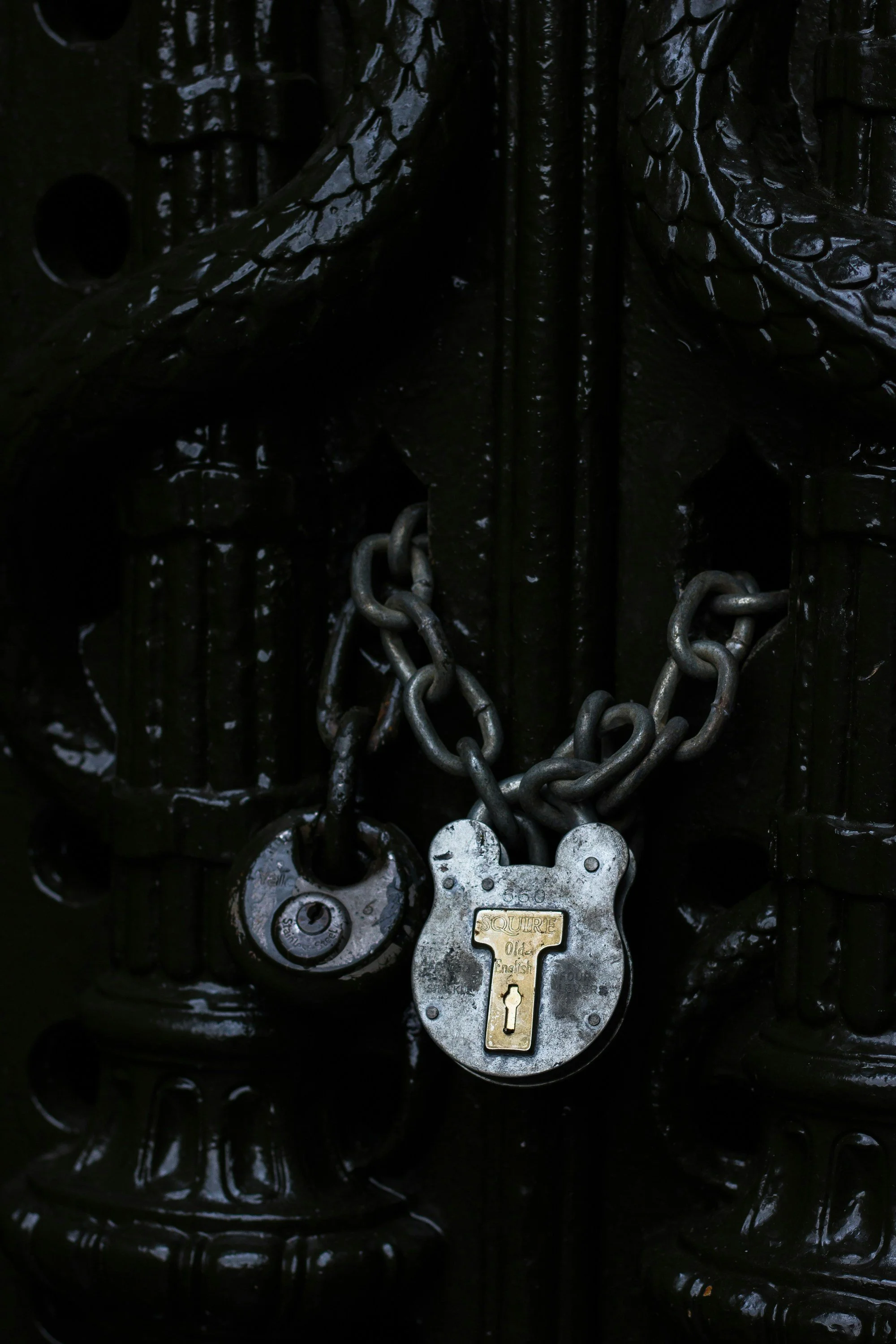 Close-up of a chained and locked old black metal gate with a padlock