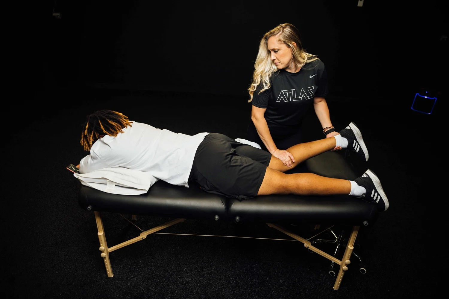 A physical therapist working hands-on through an athlete&rsquo;s knee and hamstring on the treatment table at ATLAS Rehabilitation in Pocatello