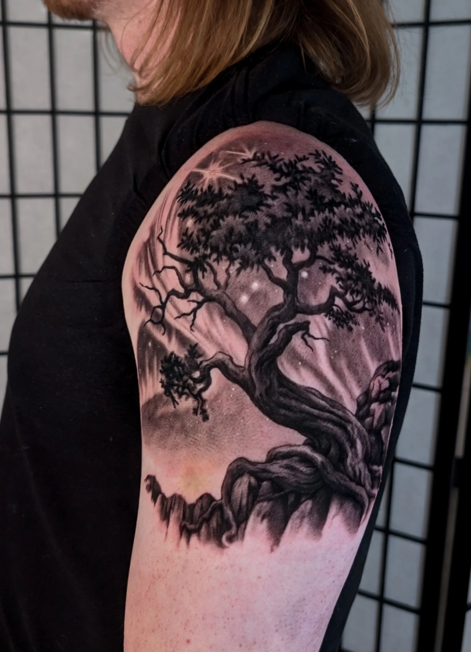 Black and grey Tree of life tattoo with northern lights in the background 