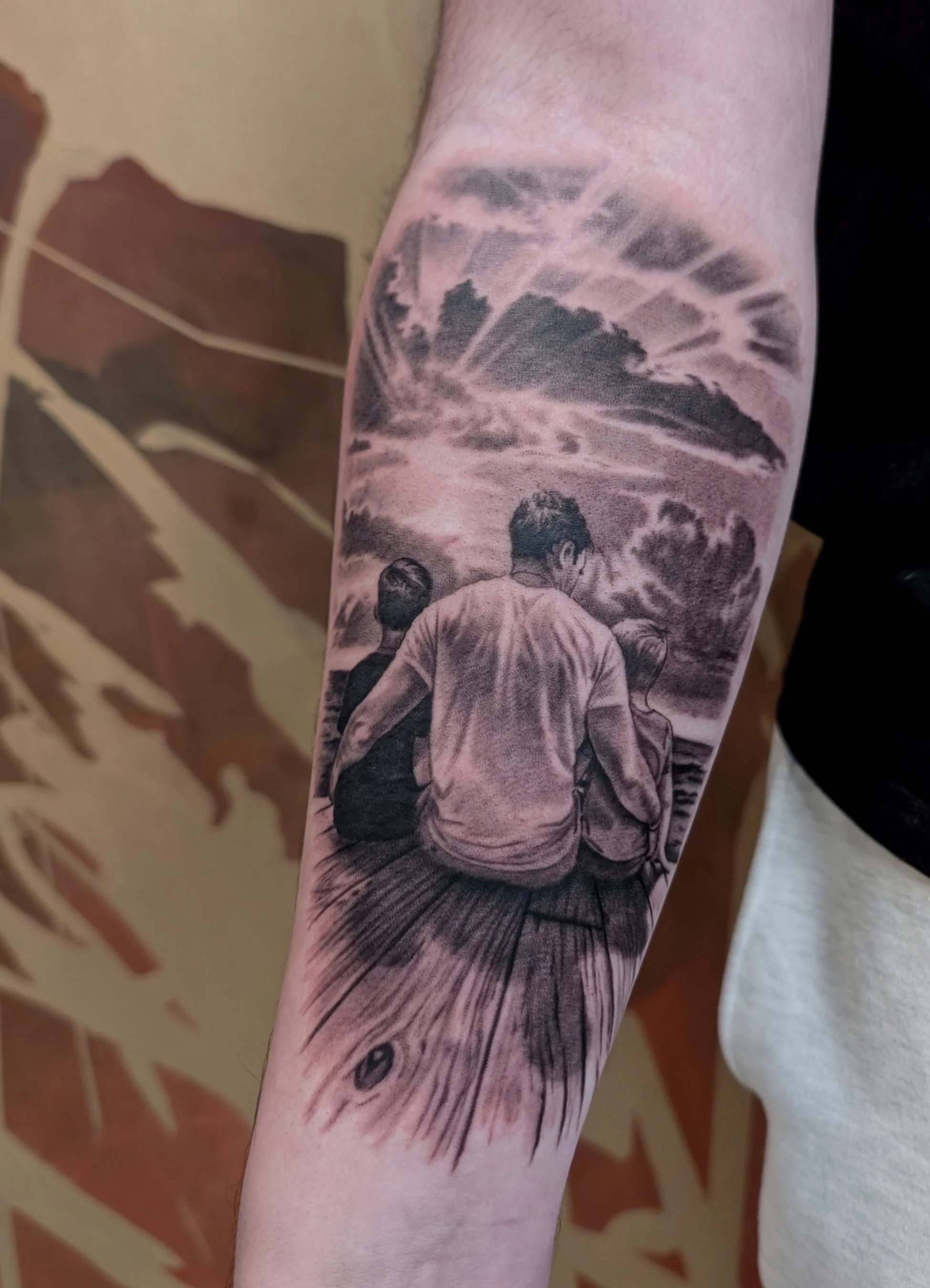 Tattoo of a family on the dock watching the sunset