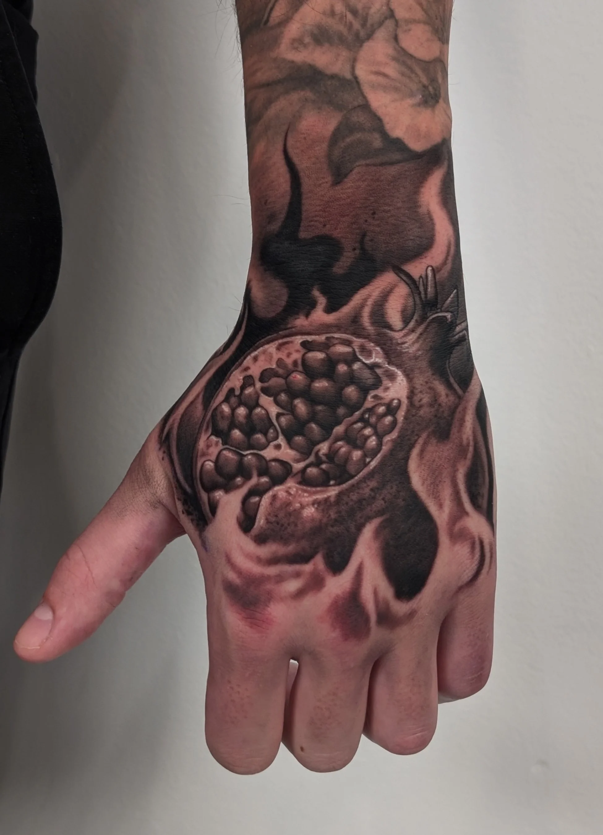 Hand tattoo with flames and pomegranate 
