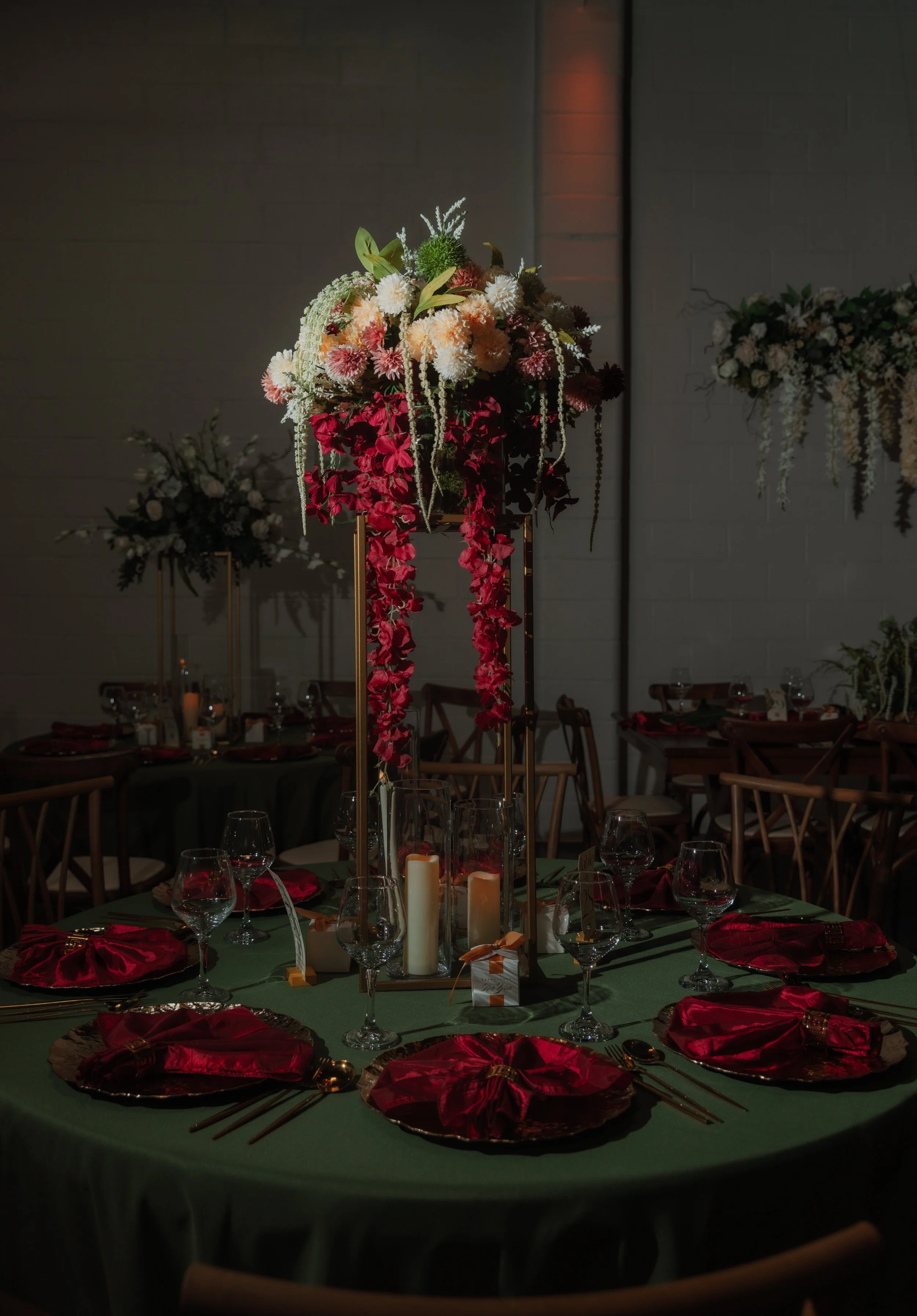 Elegant dinner table with red napkins, candles, wine glasses, and a dramatic multicolored floral centerpiece at D'Venue Albuquerque