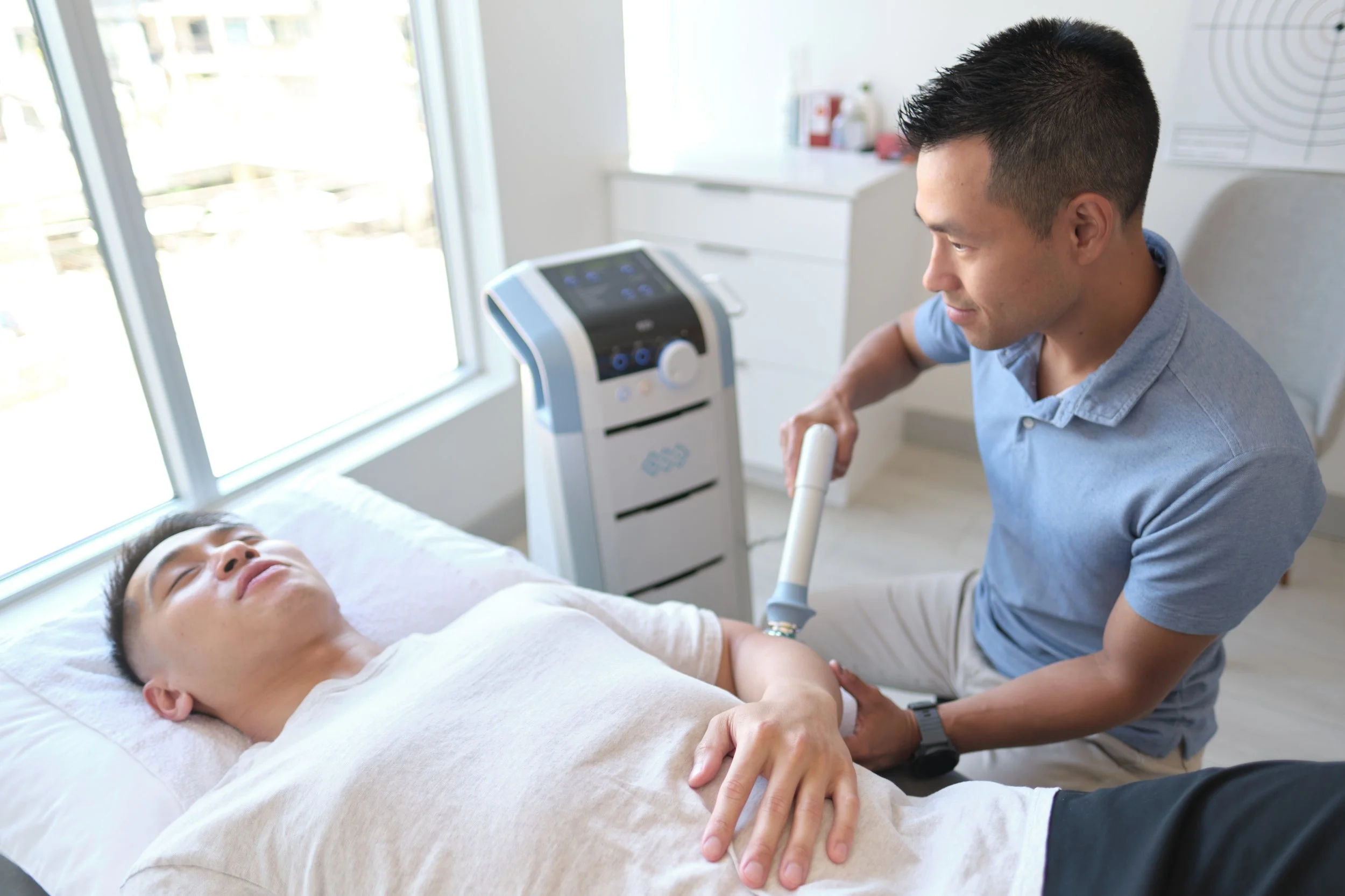 Tae Yoon physiotherapist assisting a client using shockwave at Aeris Physiotherapy in Port Moody