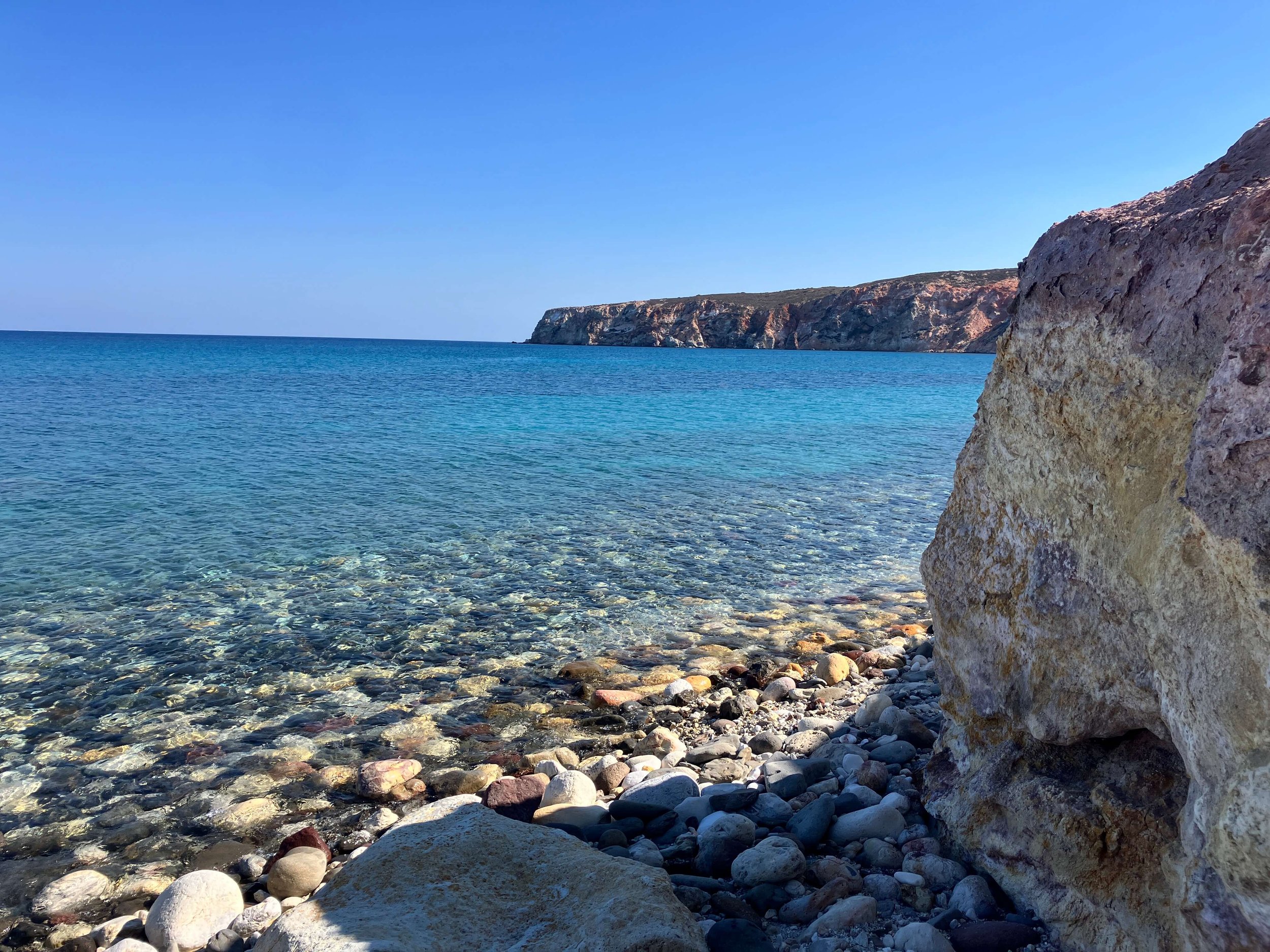 Turquoise water and colorful volcanic pebbles on Milos island.