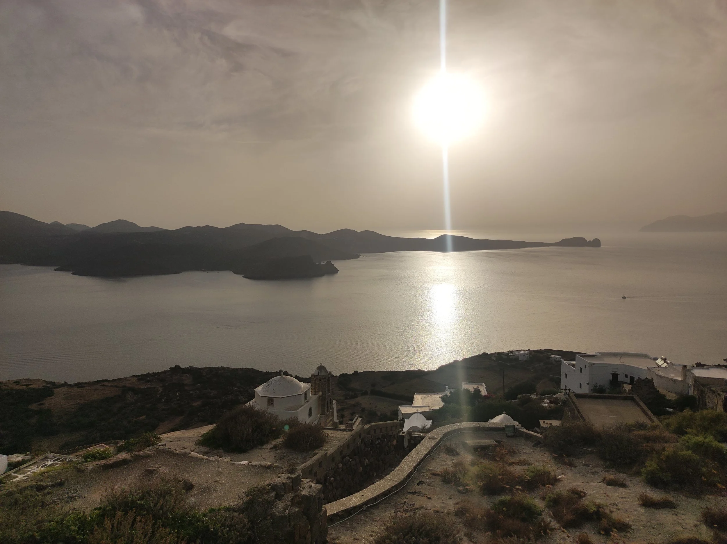 Golden hour sunset over the sea and distant islands from Plaka Castle in Milos, Greece.