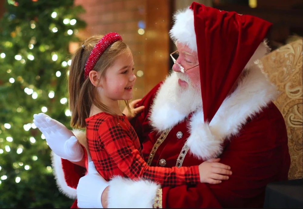 A child in Christmas pyjamas whispering to Santa at Triple S Farm