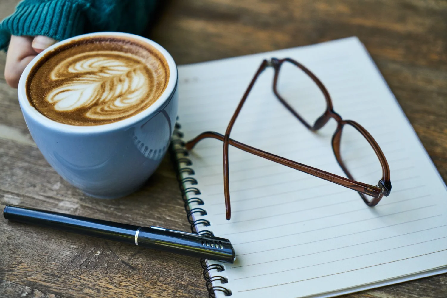 Cappuccino on a table with a notepad and readers