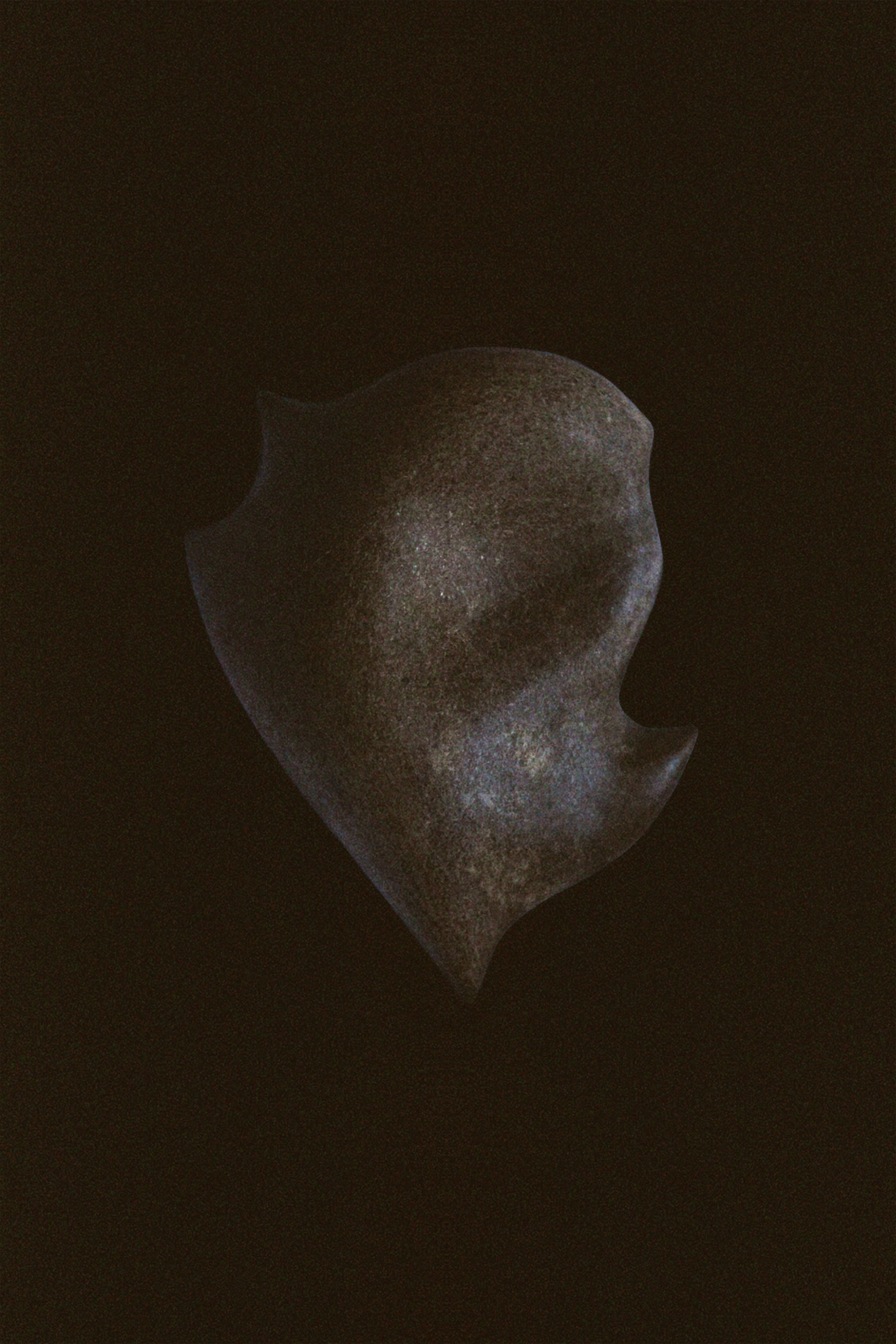 Abstract dark sculpture resembling a face in profile, set against a black background.