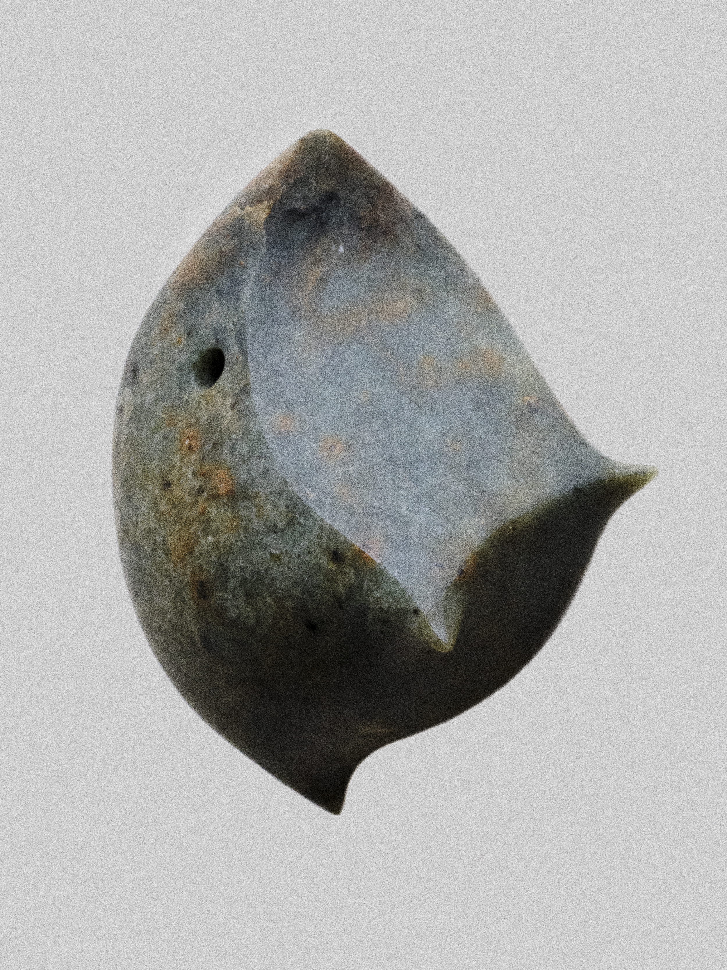 Close-up of a vintage metal excavation or archaeological tool head with a pointed end, rounded side, and a hole in the side, showing signs of rust and wear.