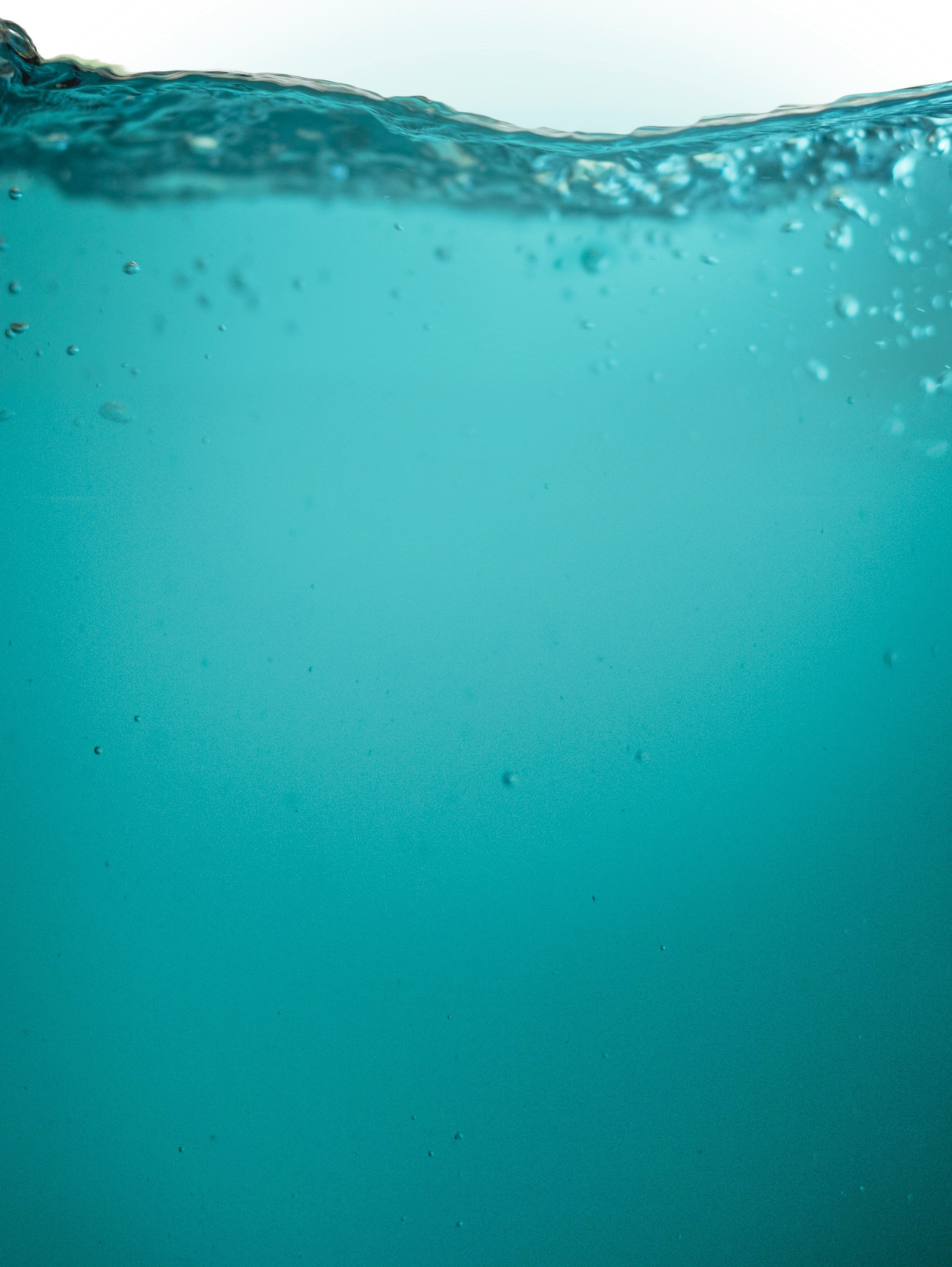 Close-up of a water surface with bubbles, showing the division between water and sky with a blurred horizon line.