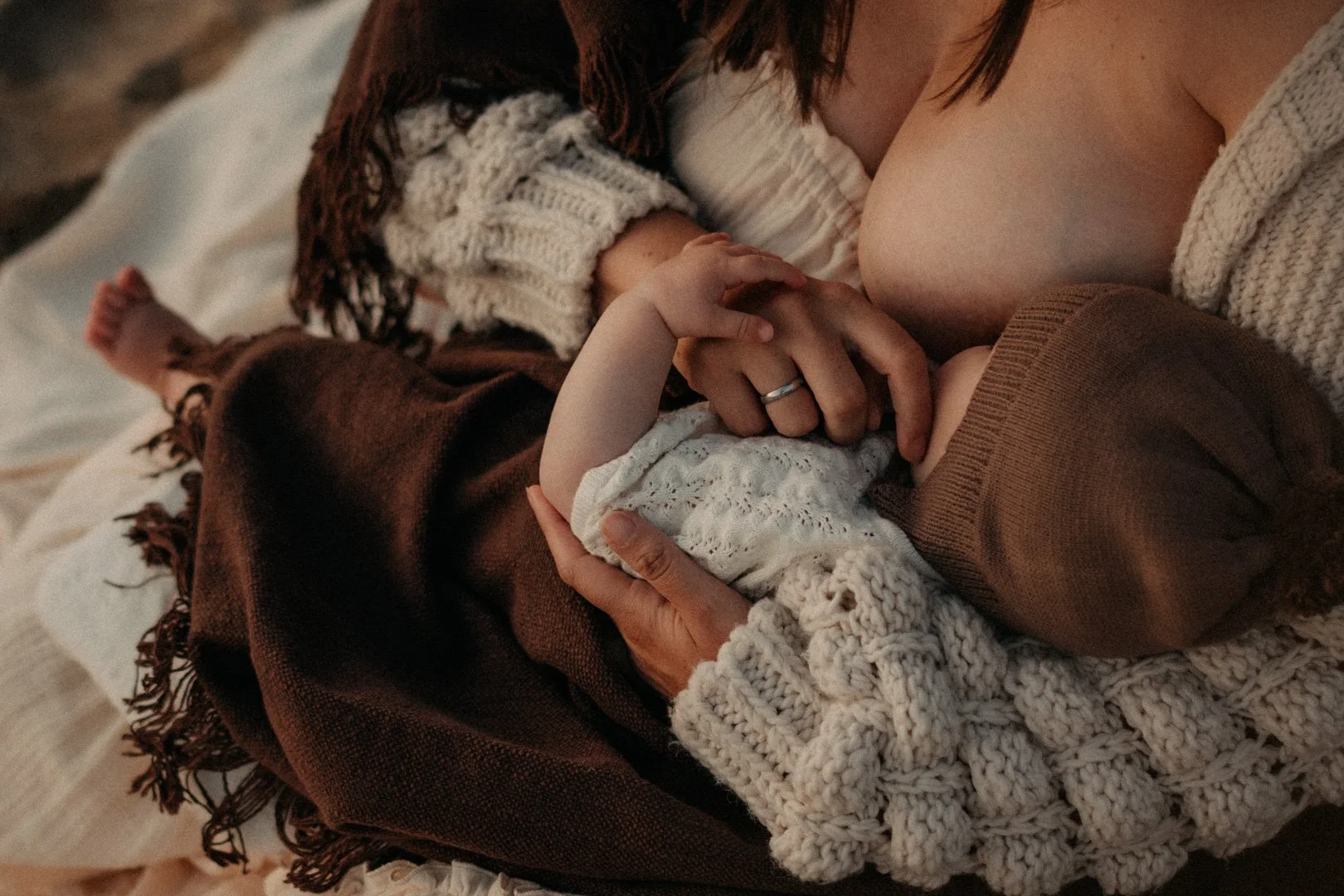 Baby stillt im Arm der Mama im weichen Licht.