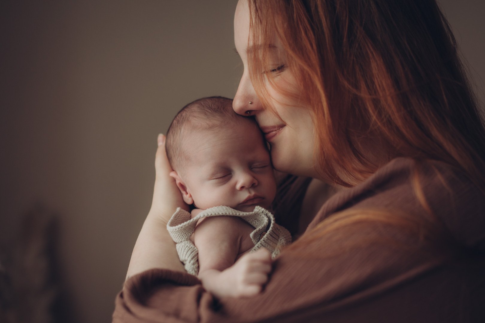 Mama kuschelt mit neugeborenem Baby auf dem Arm.