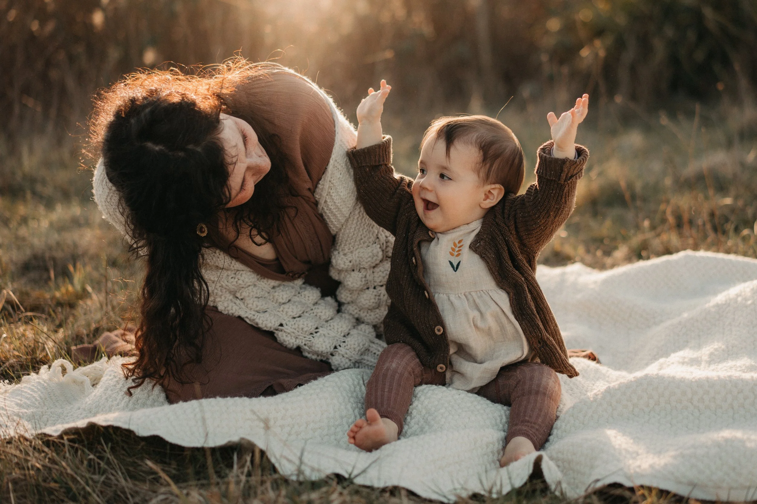 Mama und Baby sitzen im Sonnenuntergang auf der Decke