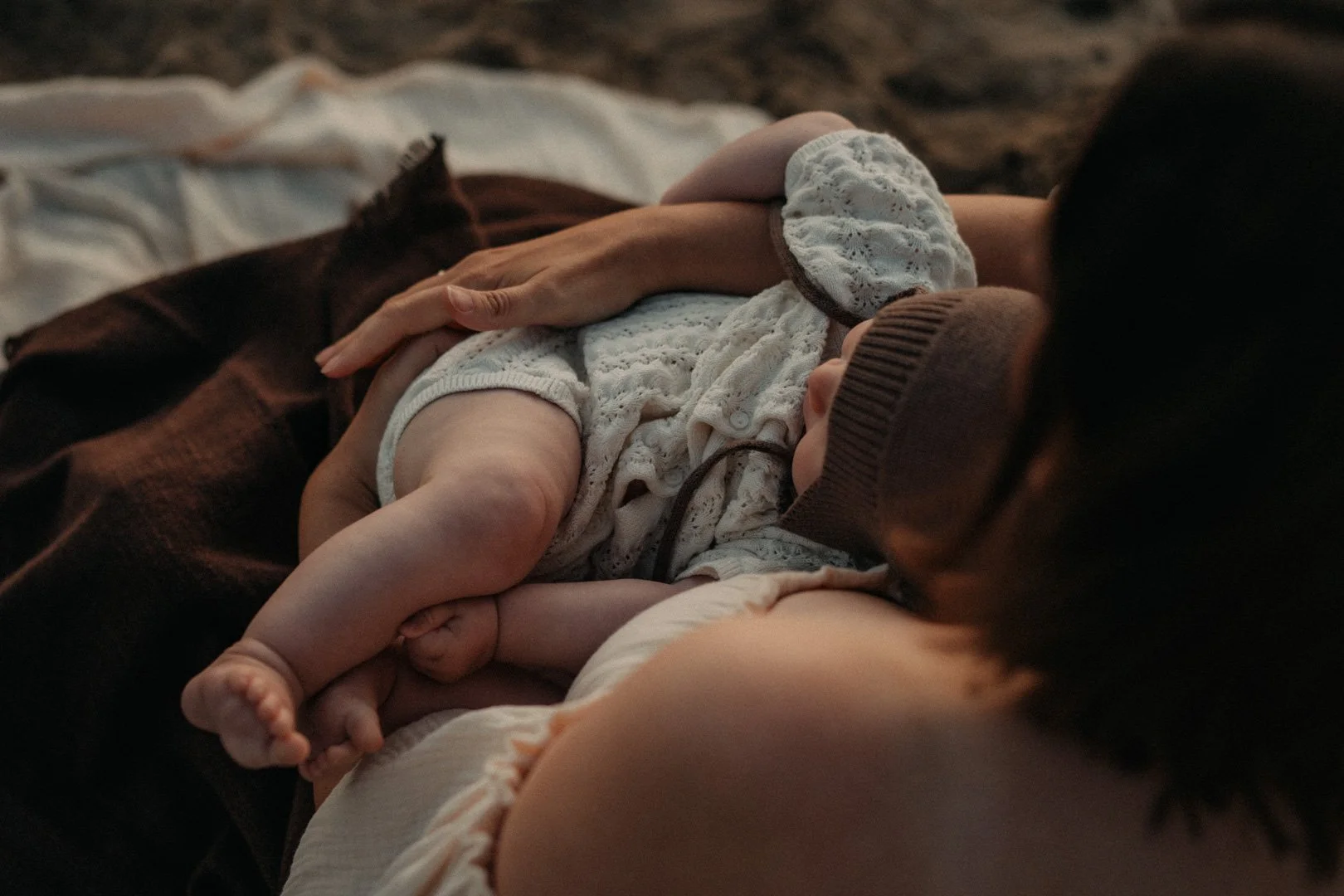 Baby liegt im Sonnenaufgang in Mamas Armen.