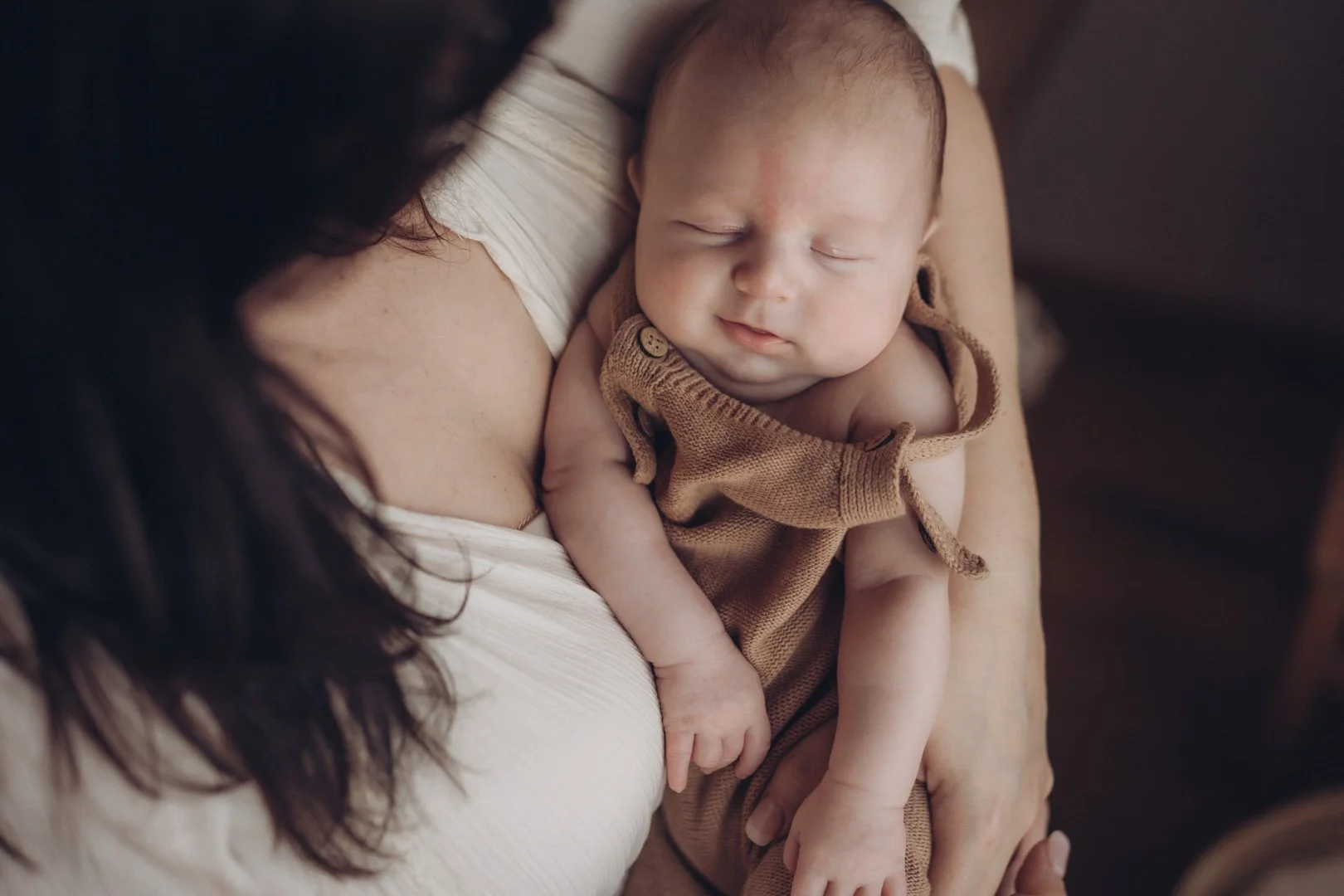 Kleines Baby liegt ganz eng angekuschelt in Mamas Armen.