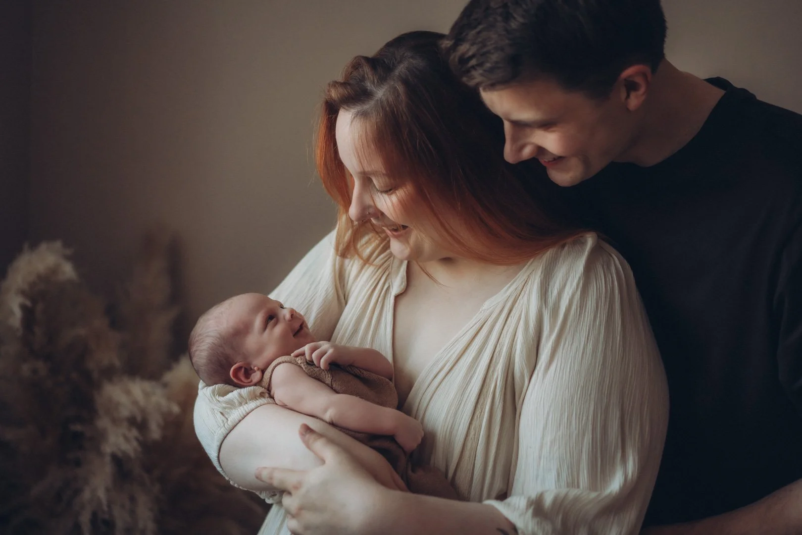 Eltern halten lachendes Baby im Arm.