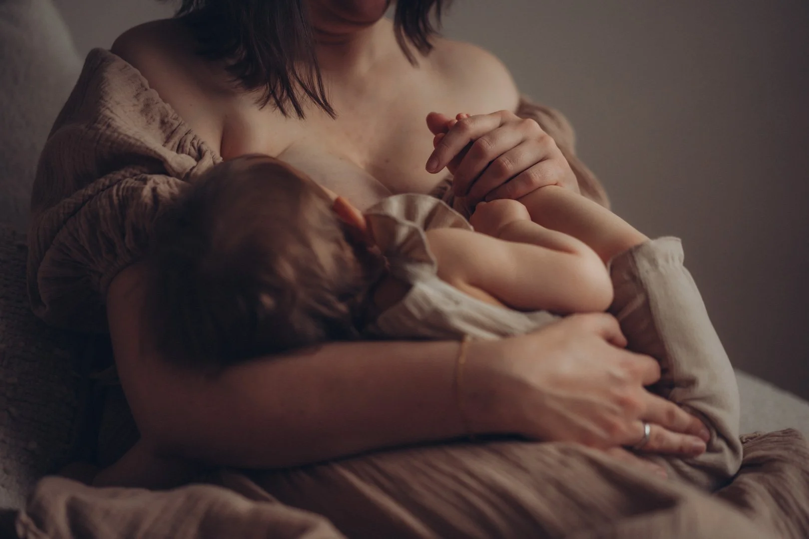 Baby liegt in Mamas Arm und stillt.