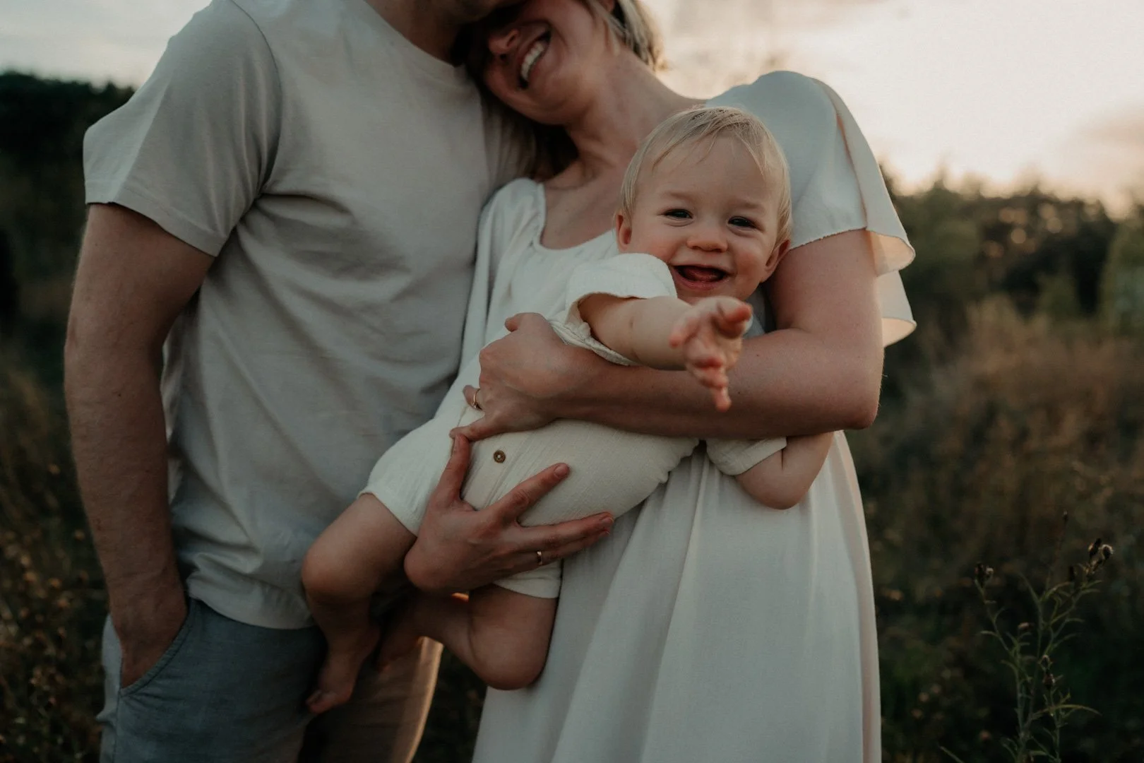 Mama und Papa halten Baby im Arm.
