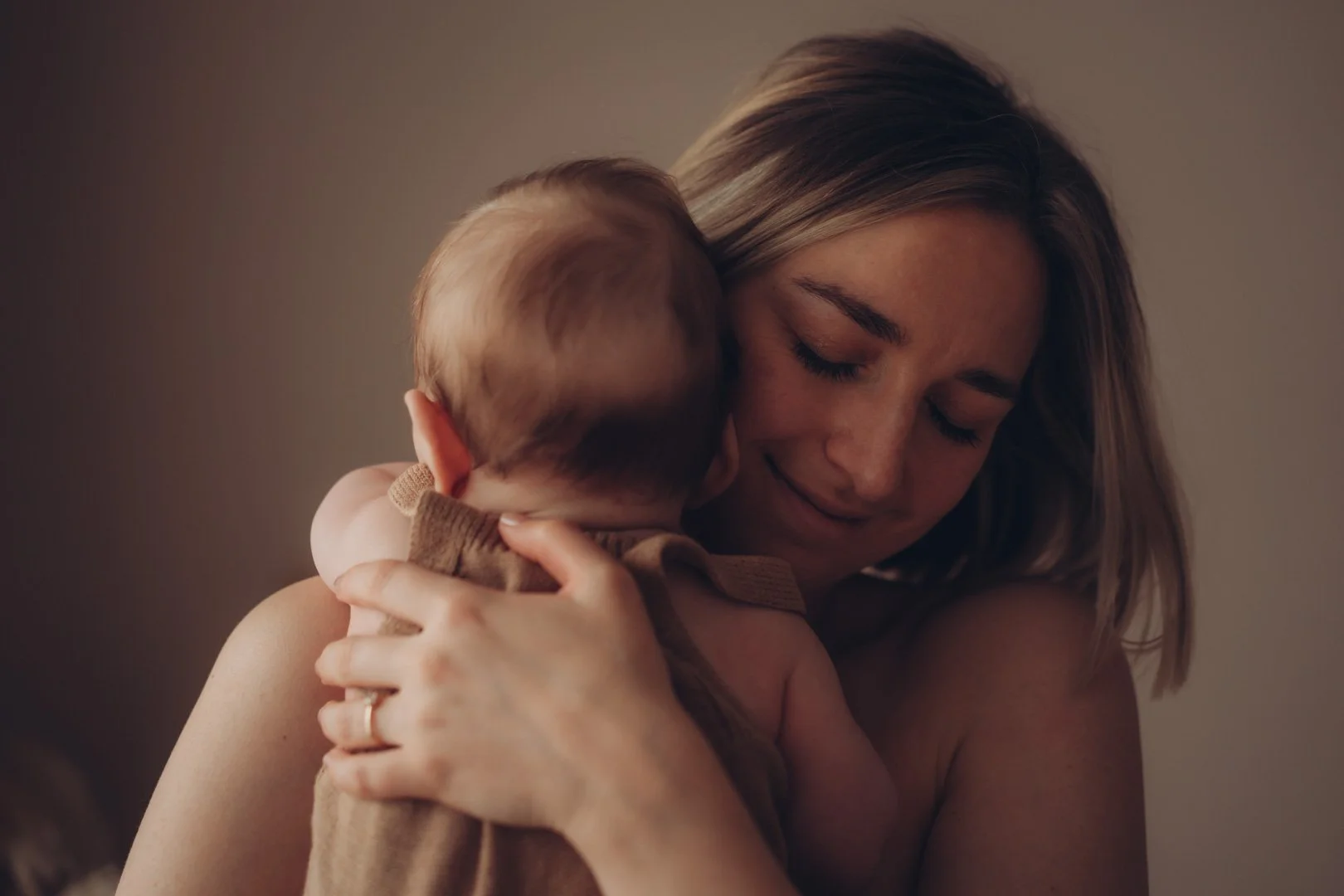 Mama kuschelt herzlich mit Baby auf dem Arm.