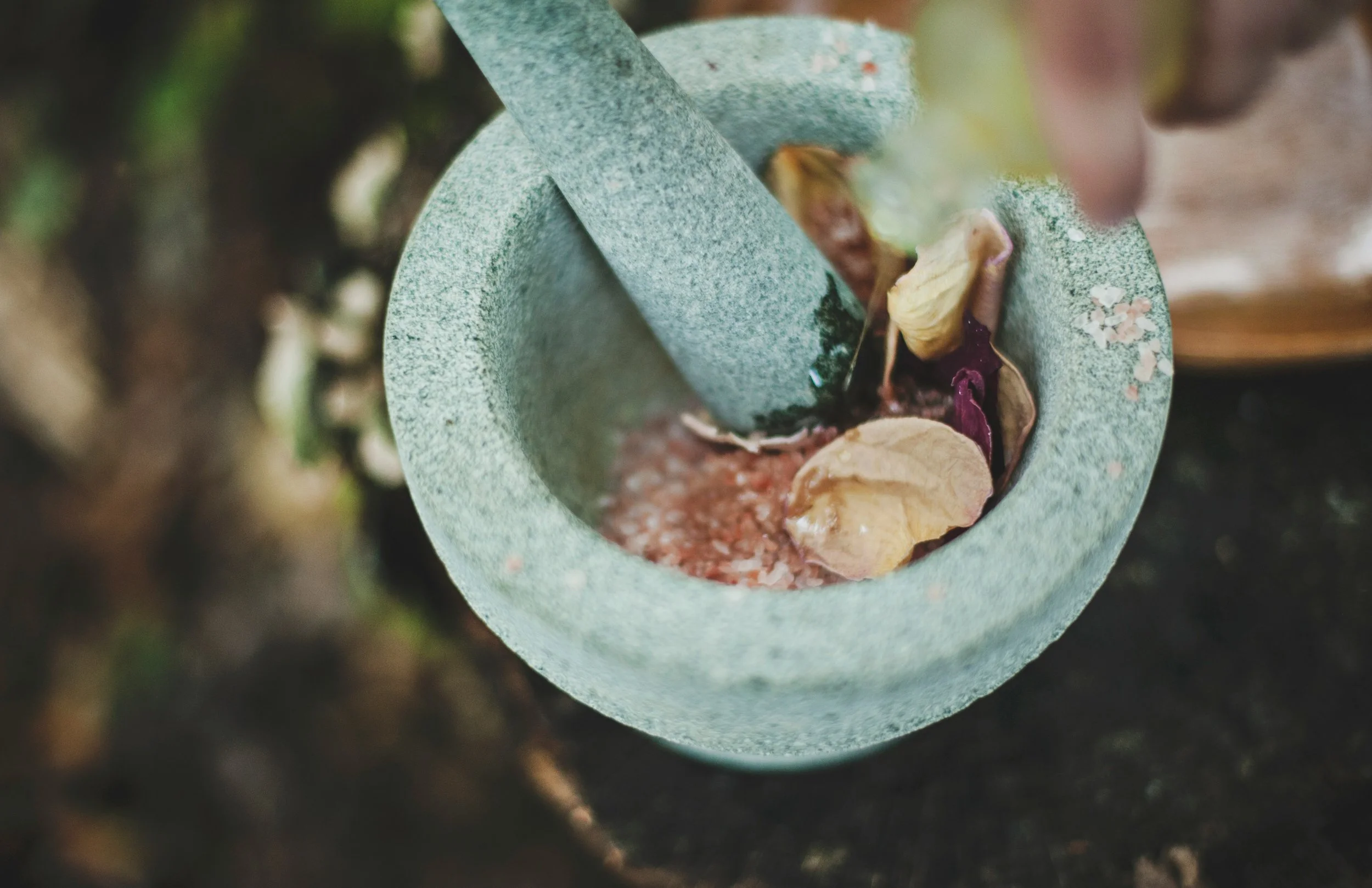 Mortar & pestle with leaves, herbs and oils