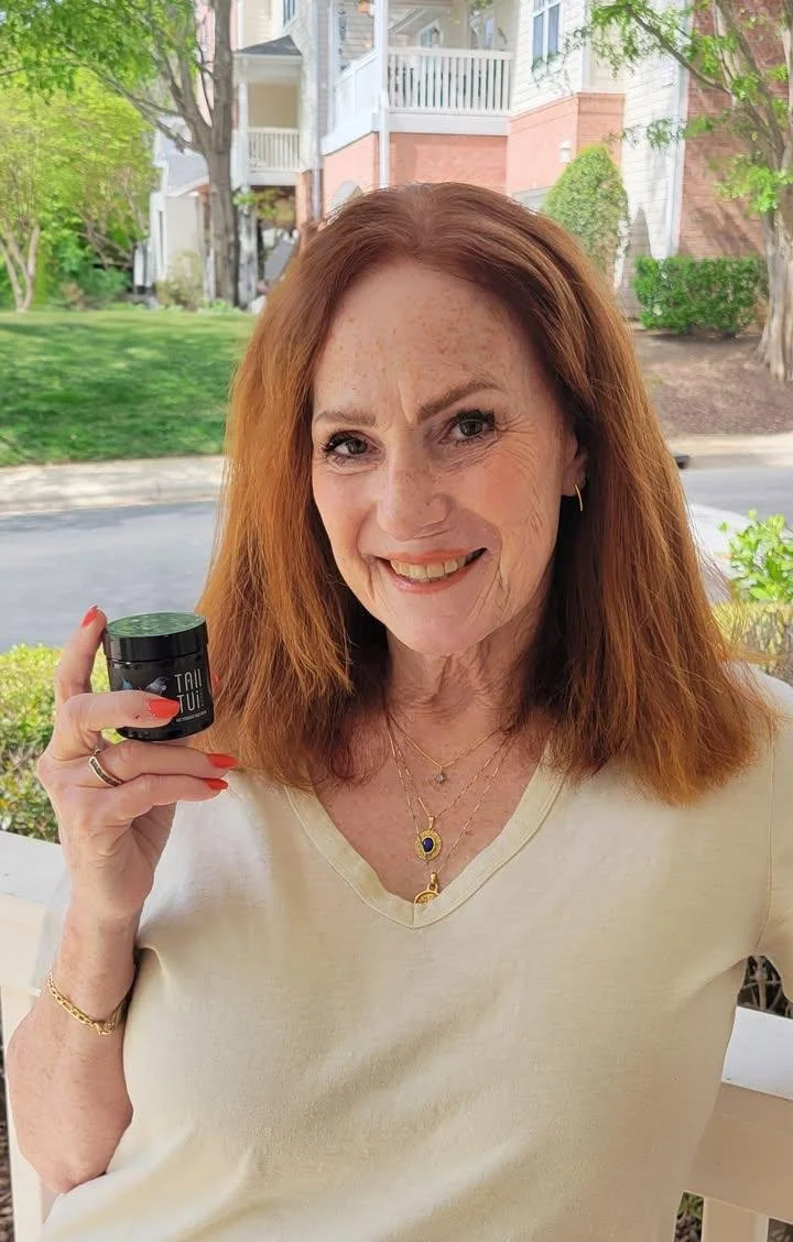 Smiling woman with red hair  pot of Tall tui