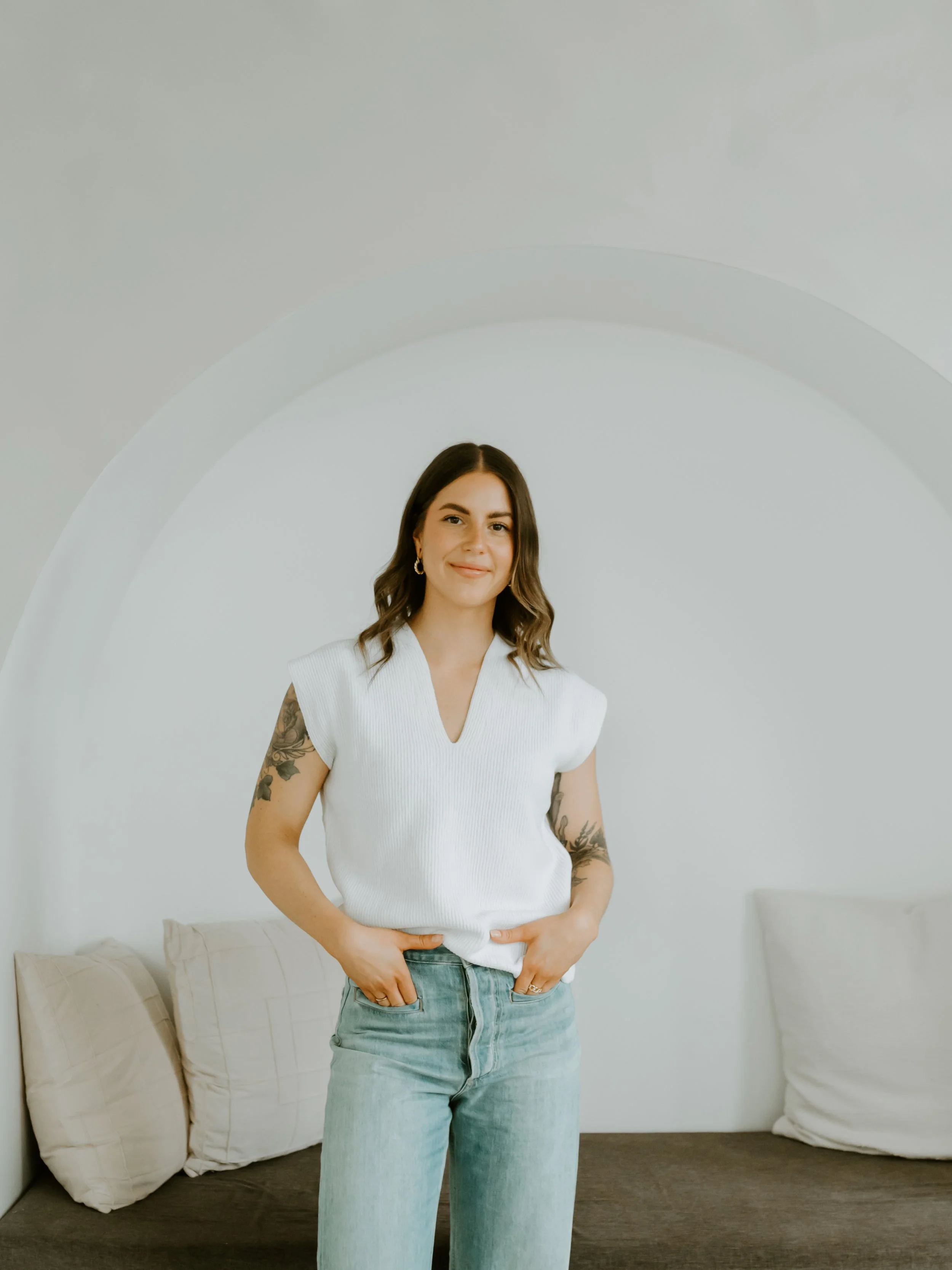 Female therapist near downtown Guelph with tattoos standing in front of a comfy nook smiling about therapy for students in Ontario