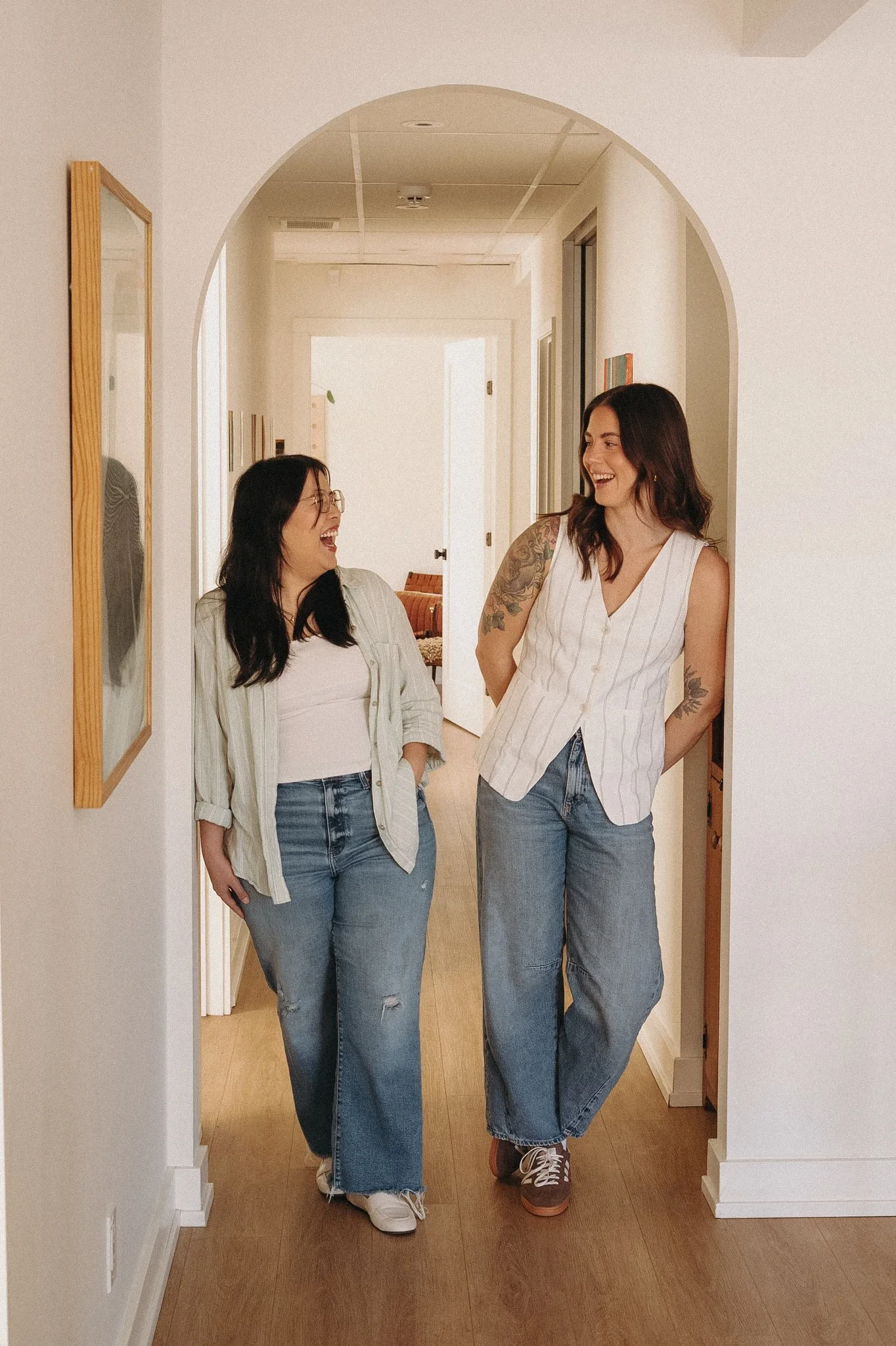 2 female therapists standing in an archway in their Guelph therapy office laughing.