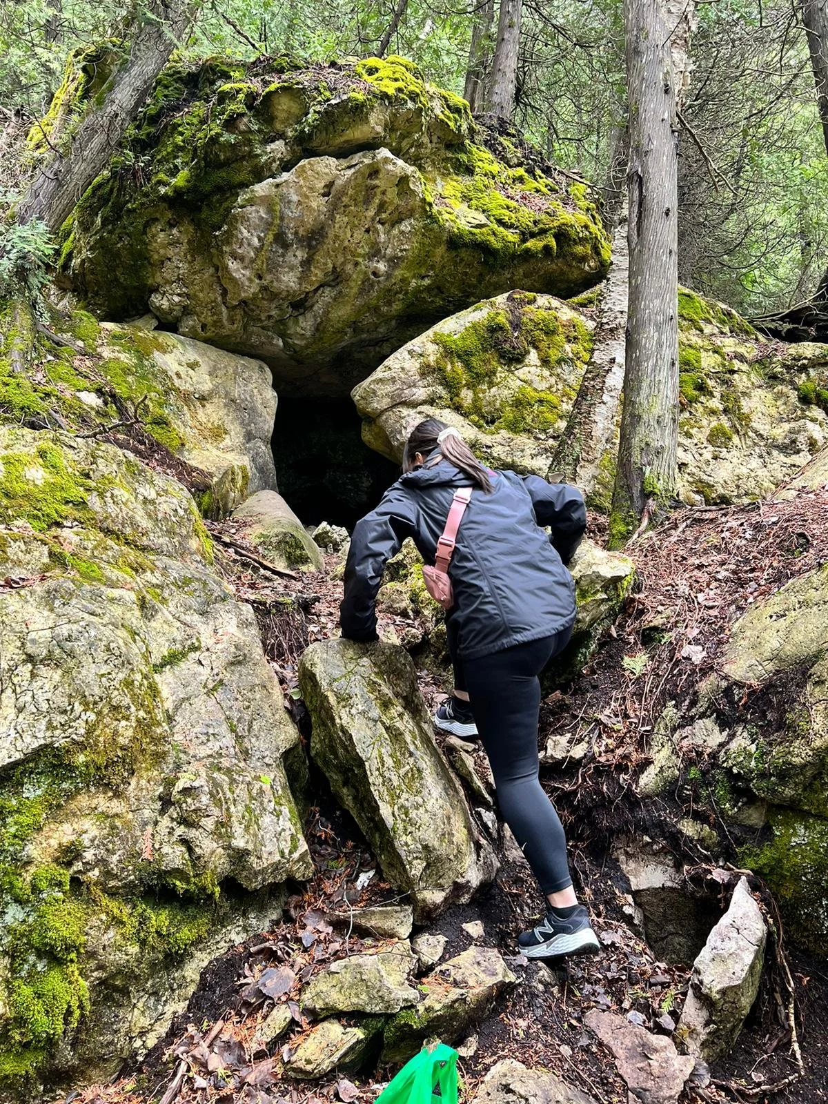 An Asian female therapist in downtown Guelph climbing on rocks thinking about therapy for burnout in Ontario, on a hike