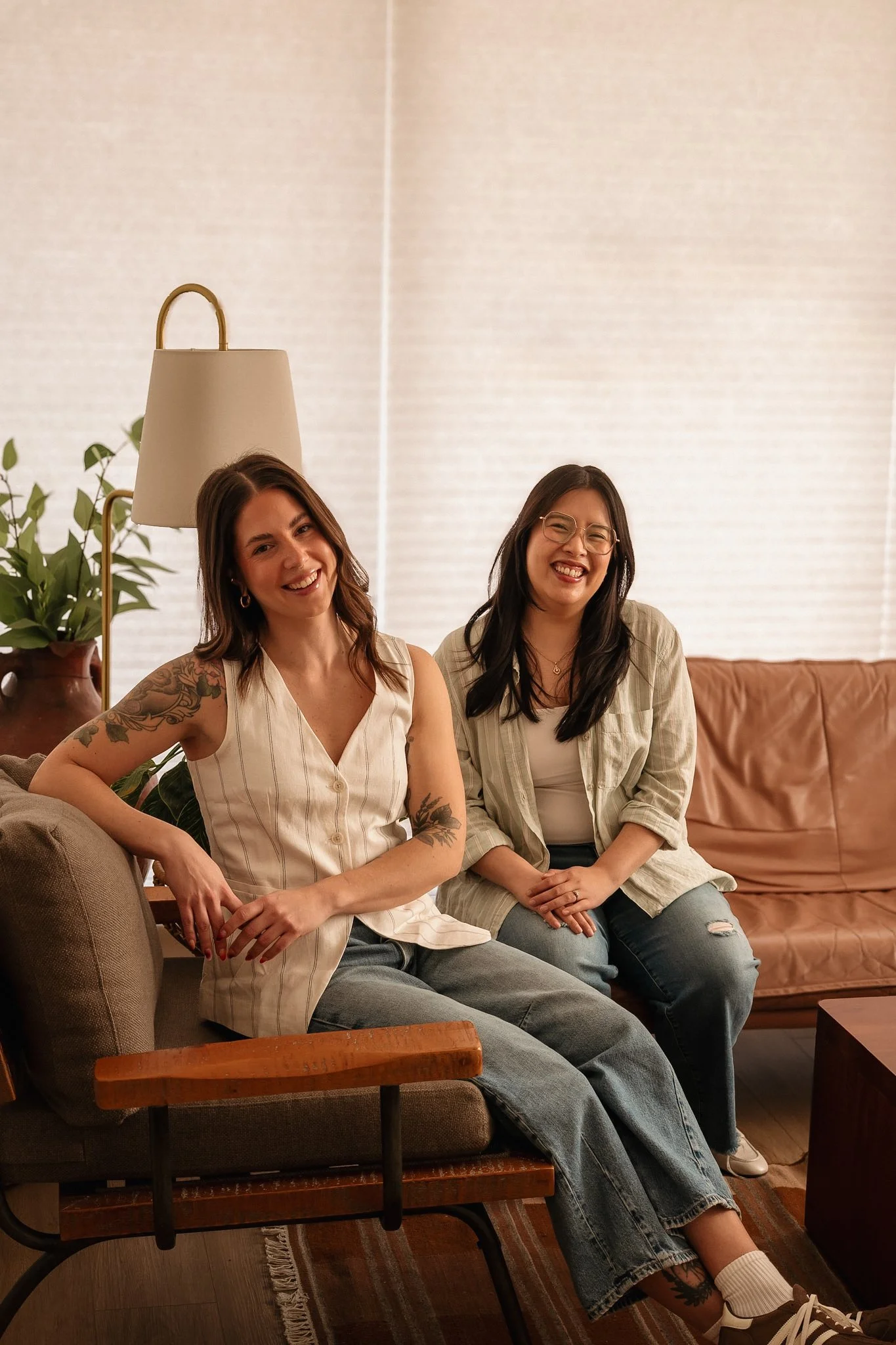 2 couples therapists sitting on their Guelph counselling couch smiling.