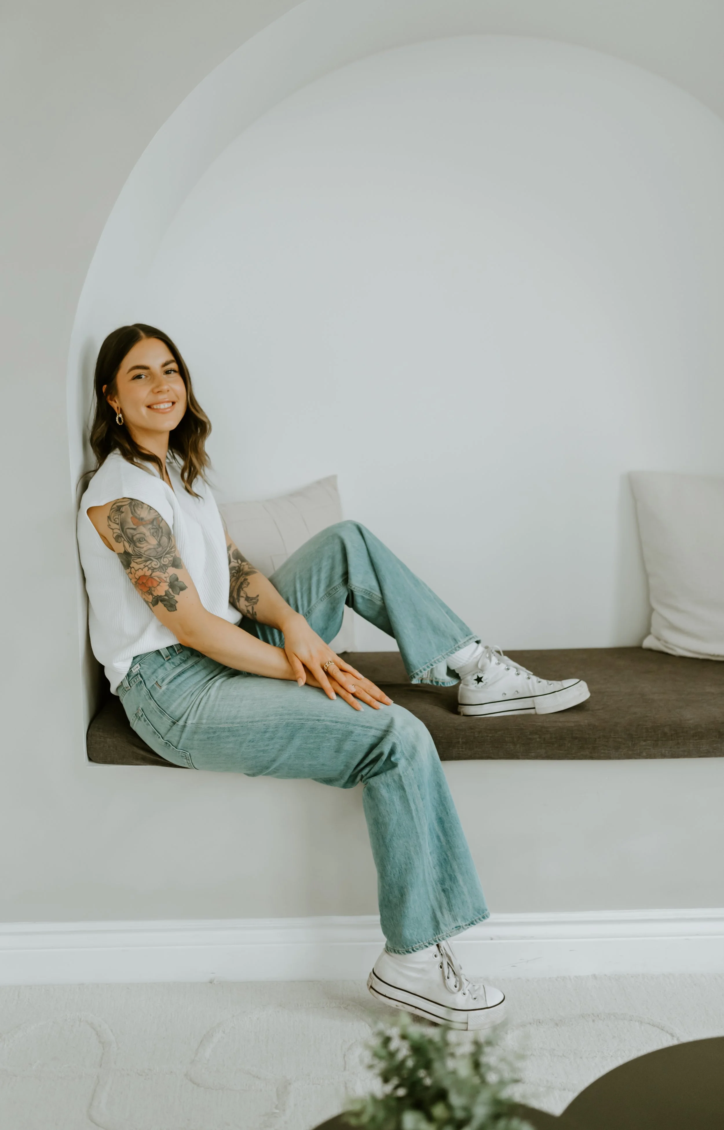 Female therapist near downtown Guelph with tattoos sitting in a comfy nook smiling about therapy for students in Ontario