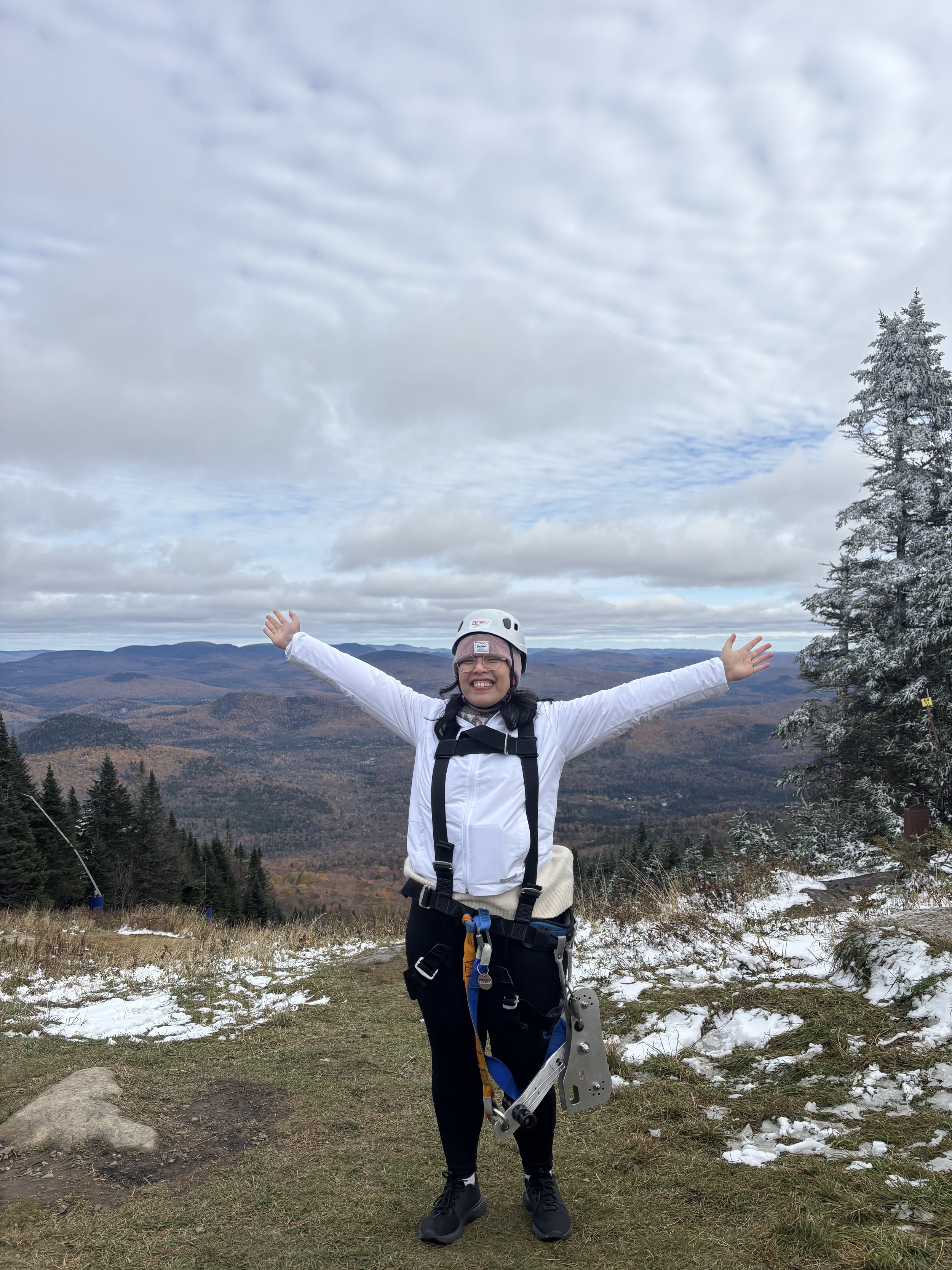 An Asian female therapist in downtown Guelph smiling about therapy for imposter syndrome in Ontario, at the top of a mountain