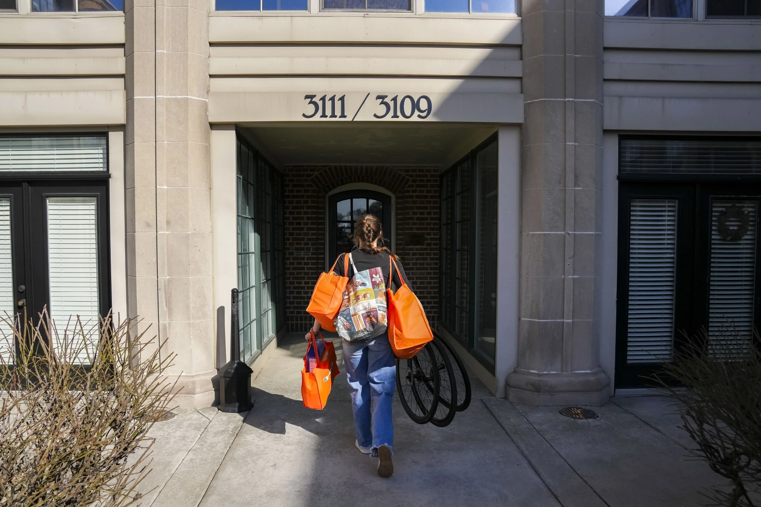 Stephanie Lawrence carries groceries and bike wheels into her apartment building in Indianapolis, Ind., on Tuesday, March 11, 2025. Some of Lawrence’s first memories on the track are when her parents, who both ride, took their kids to a velodrome in 