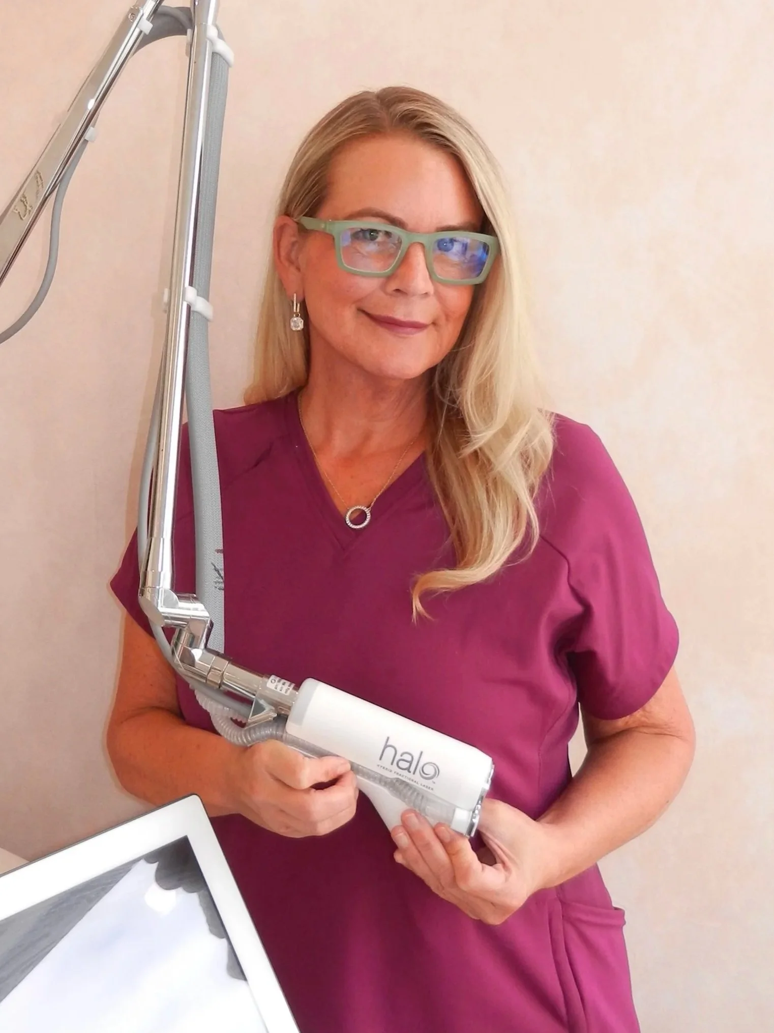 A woman wearing glasses and a purple medical uniform holds a dental tool labeled 'halo,' standing in a clinical setting.