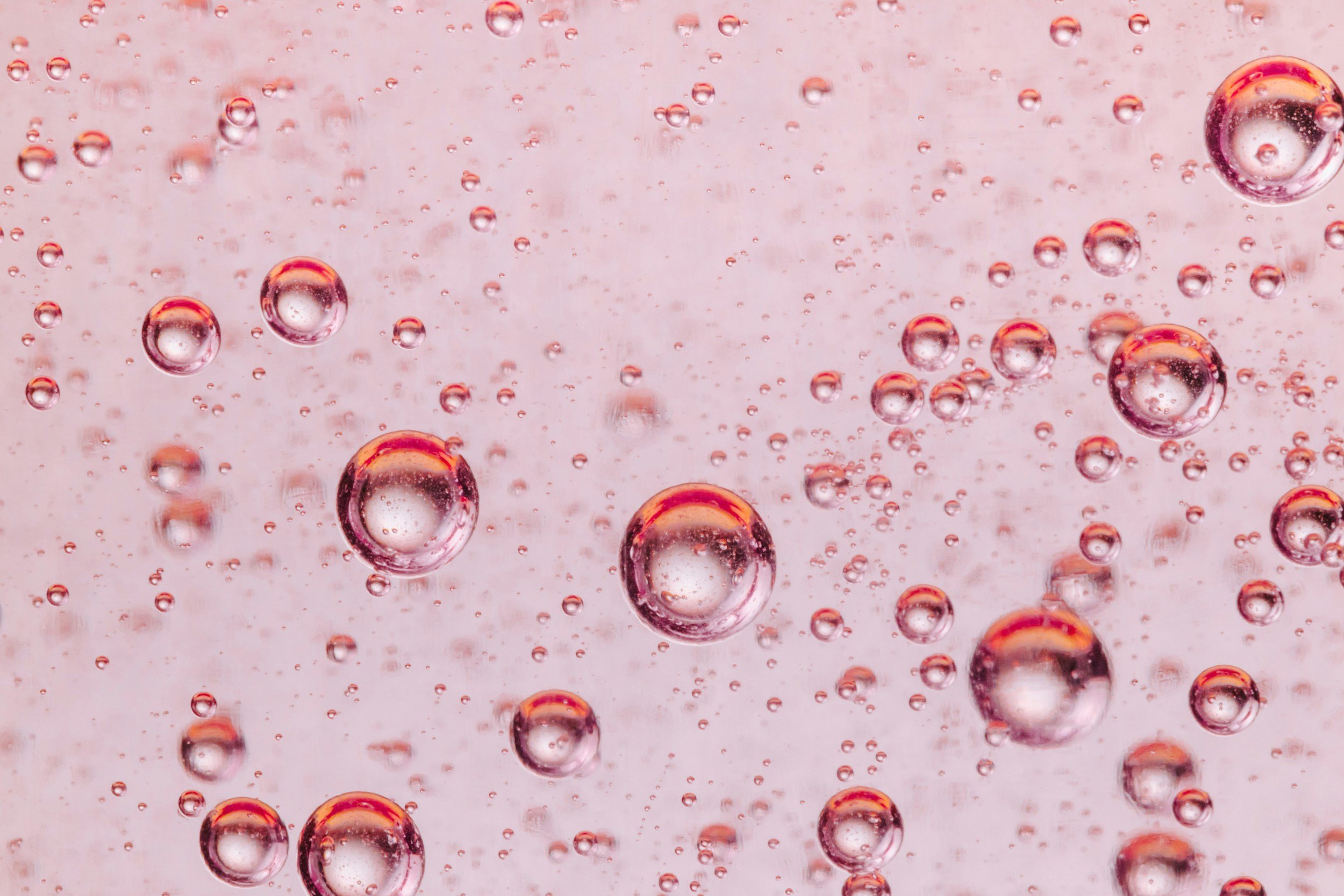 Close-up of bubbles in a pink carbonated beverage.