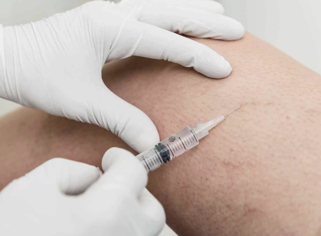 A medical professional wearing gloves administering an injection into a person's skin.