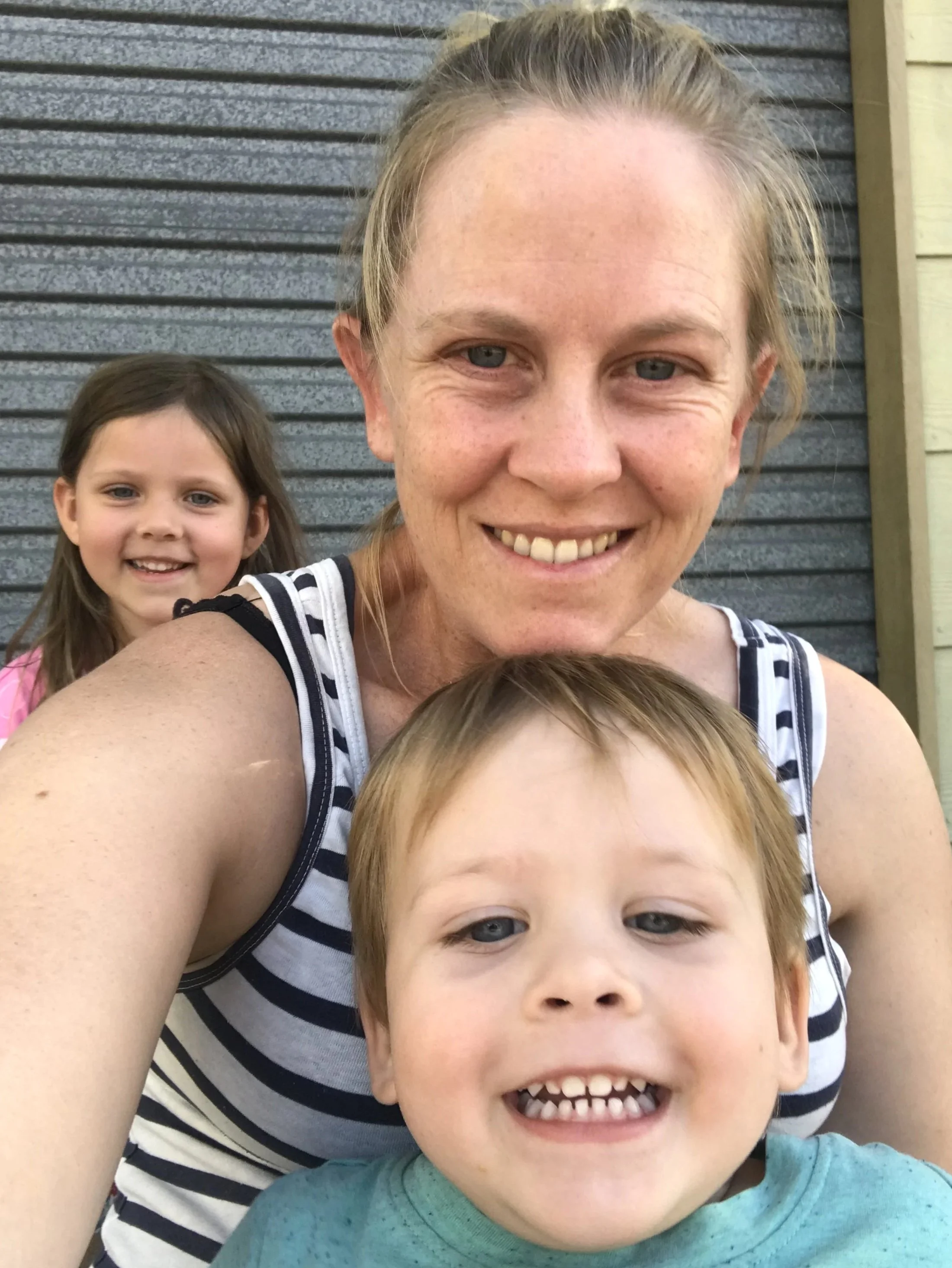 Smiling but exhausted looking mother with two small children