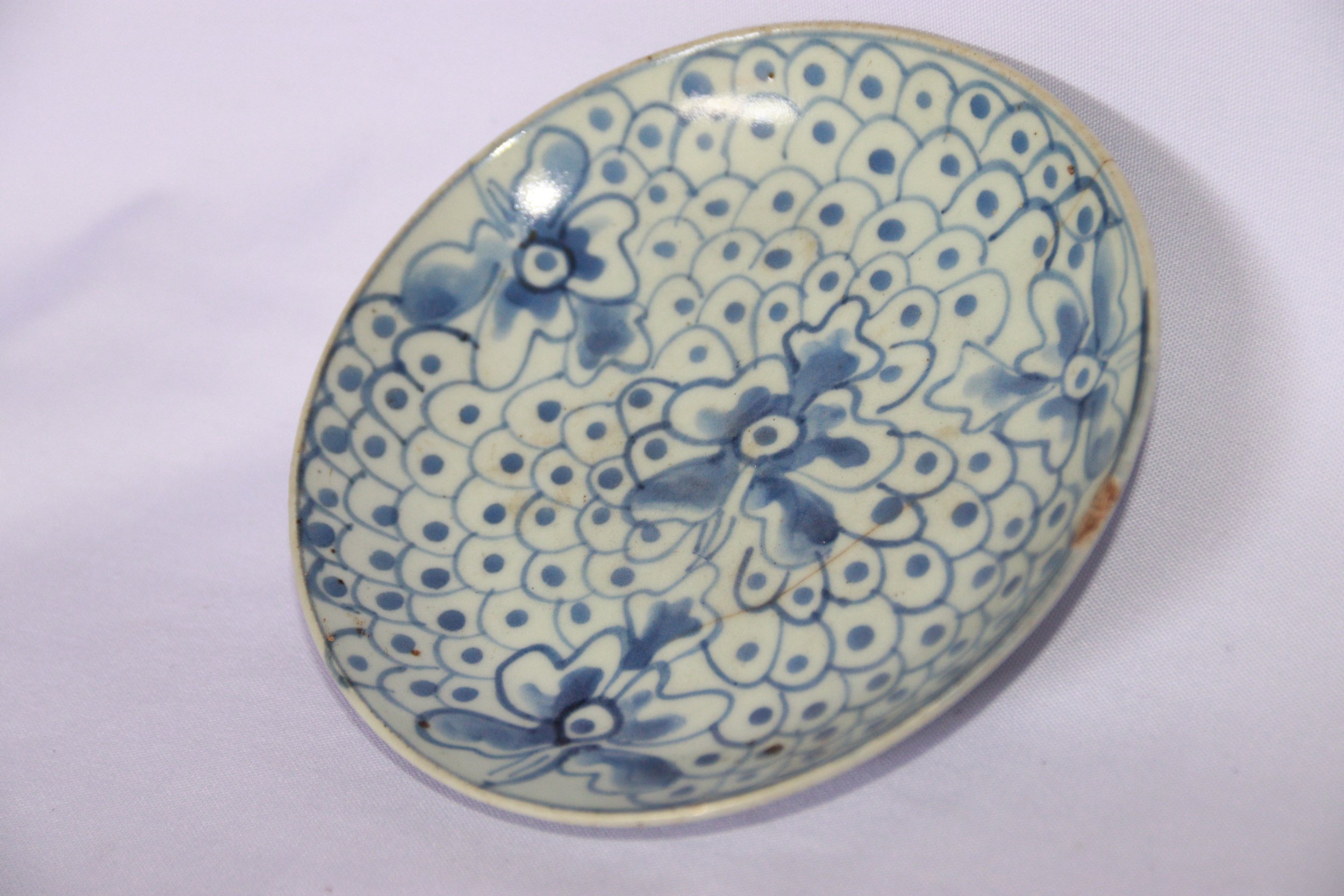 archive number: r-2-024
object reference: 
Qing-style plate
origin: China (assumed)
date: Qing Dynasty
notes: This plate is made of ceramic, predominantly white with a blue motif. The main motif is a pattern of overlapping circles or scales, creating