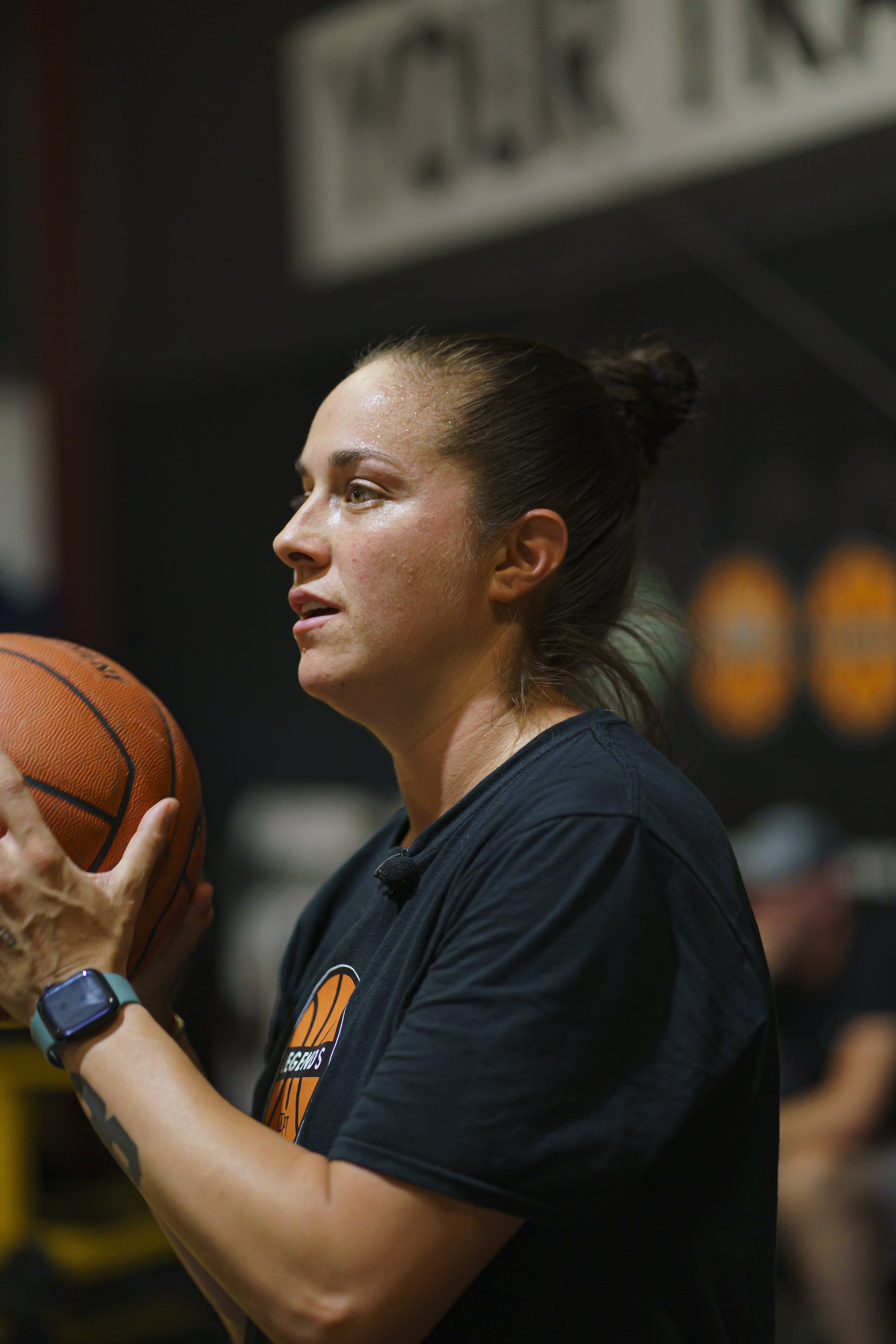 A woman in athletic attire, holding a basketball in a gym or sports setting. Kelsey Plum.