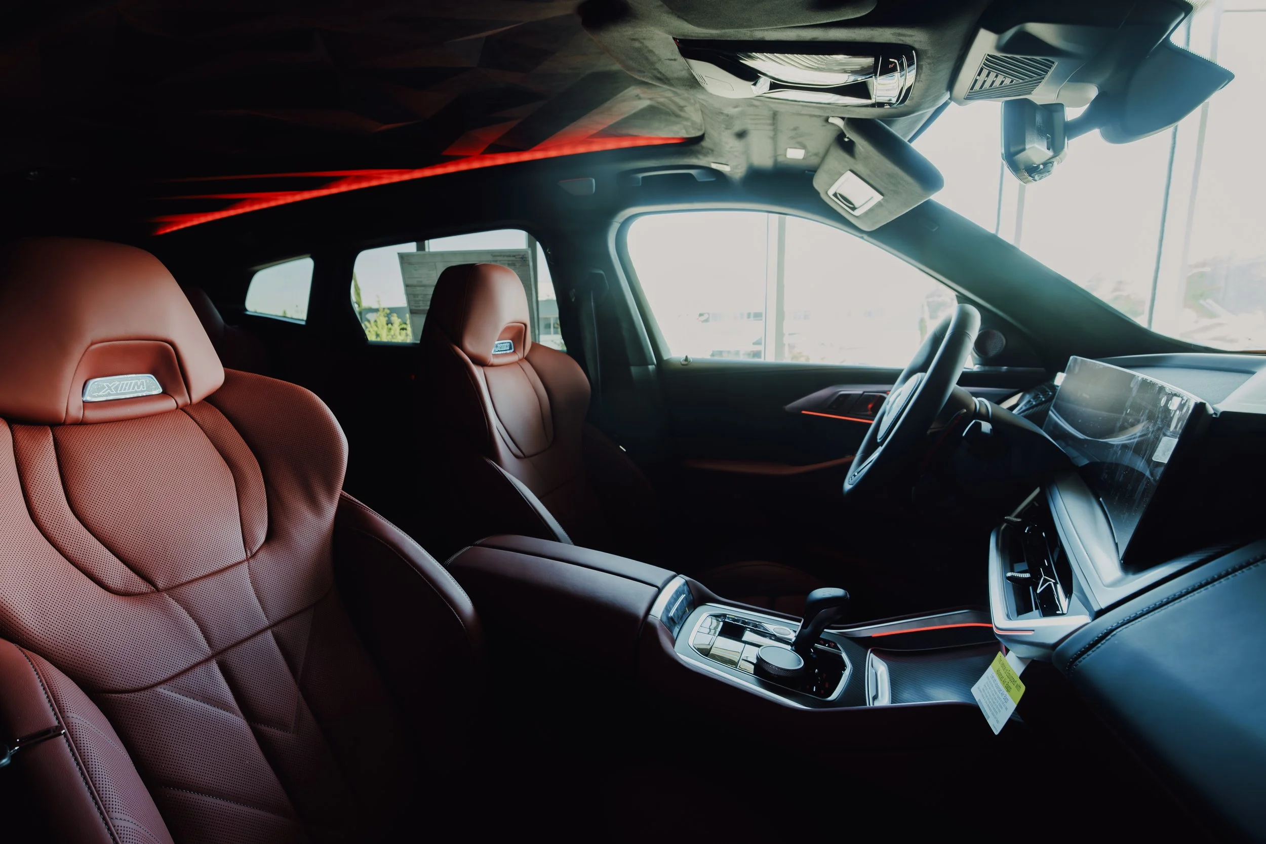 Interior of a luxury car with red leather seats, a modern dashboard, and a large digital display screen.