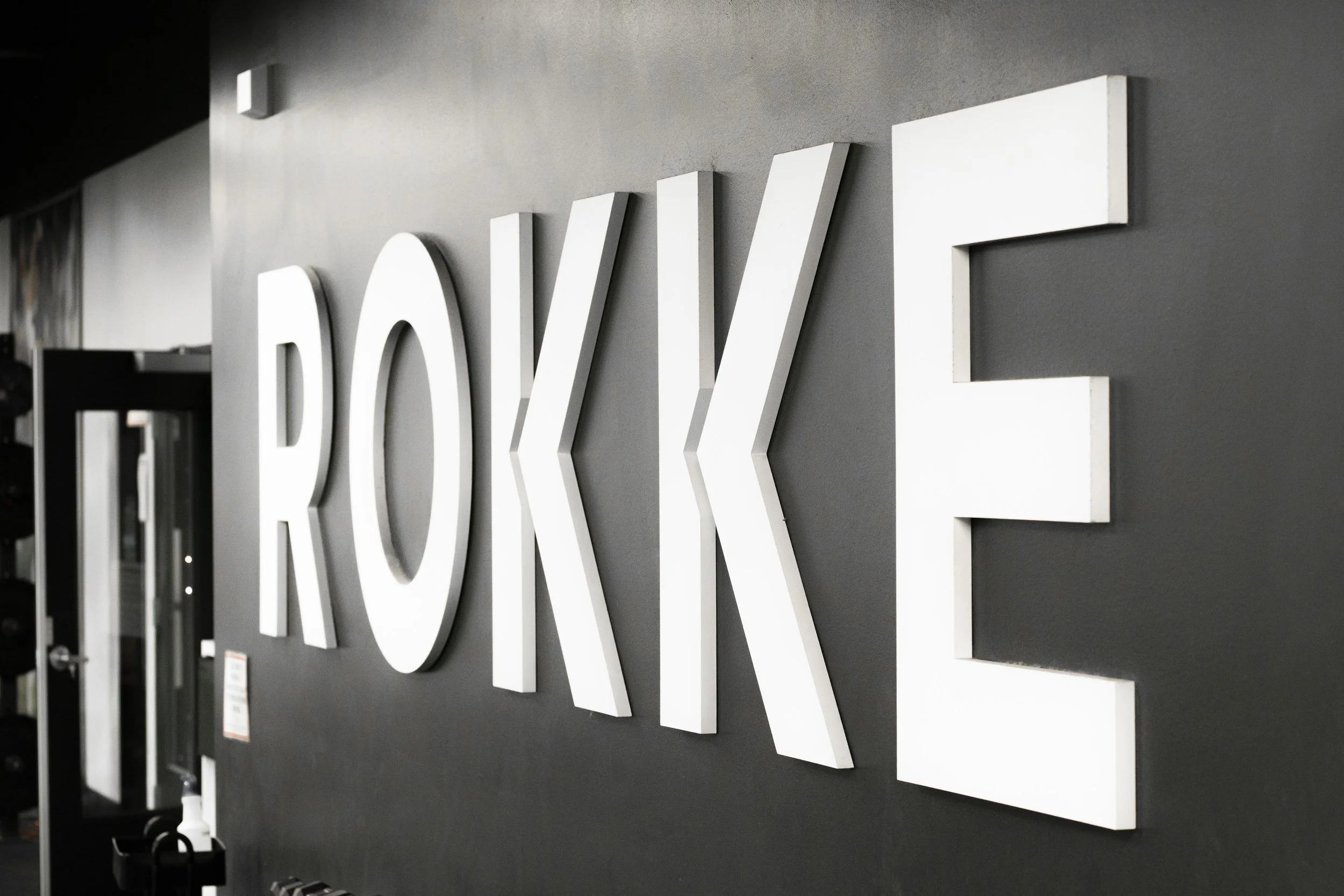 Close-up of large white three-dimensional letters spelling 'ROK' mounted on a dark wall.