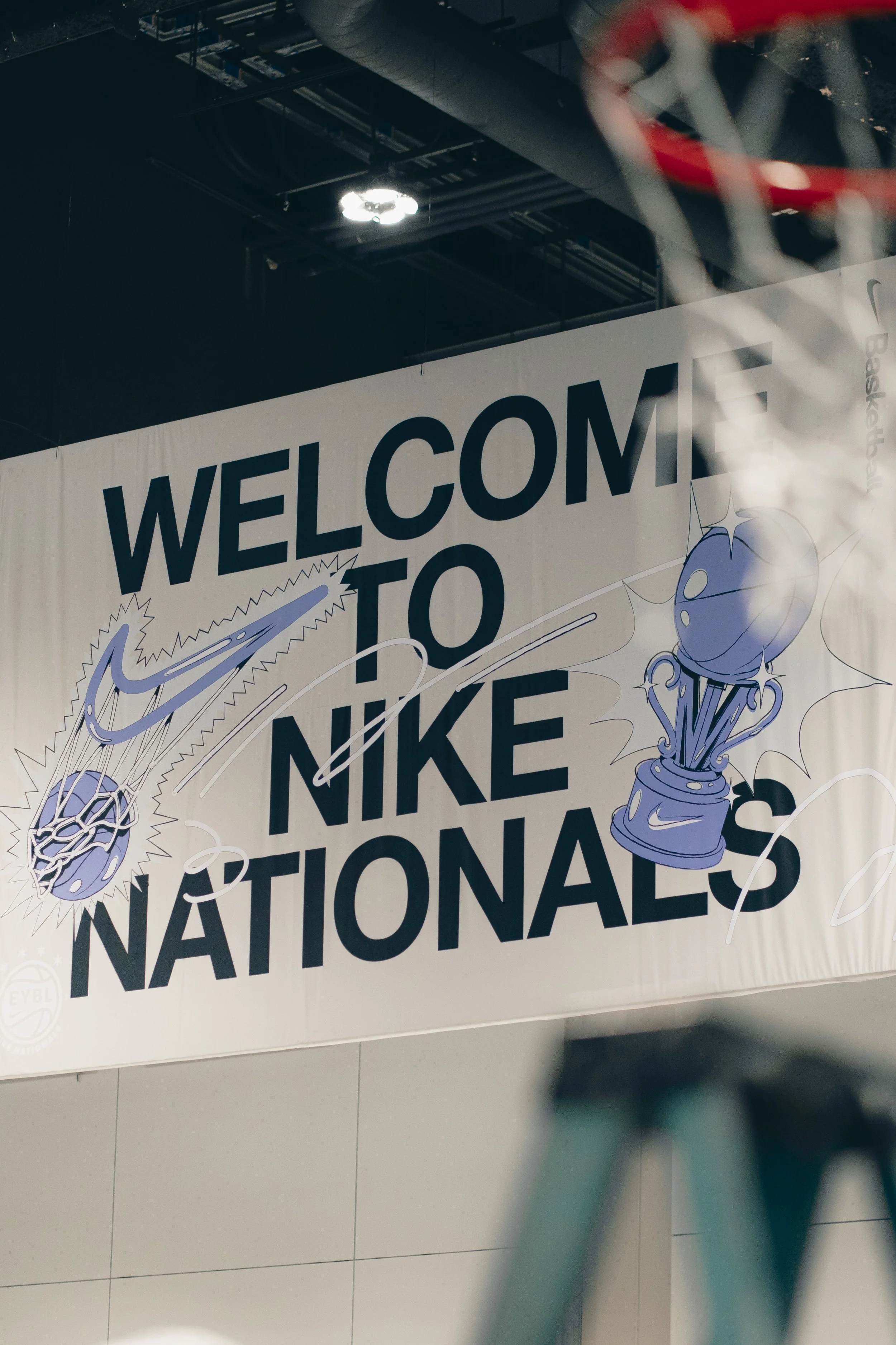 A large banner with the text 'Welcome to Nike Nationals' and illustrations of sports equipment, partially obscured by a bicycle chain in the foreground.